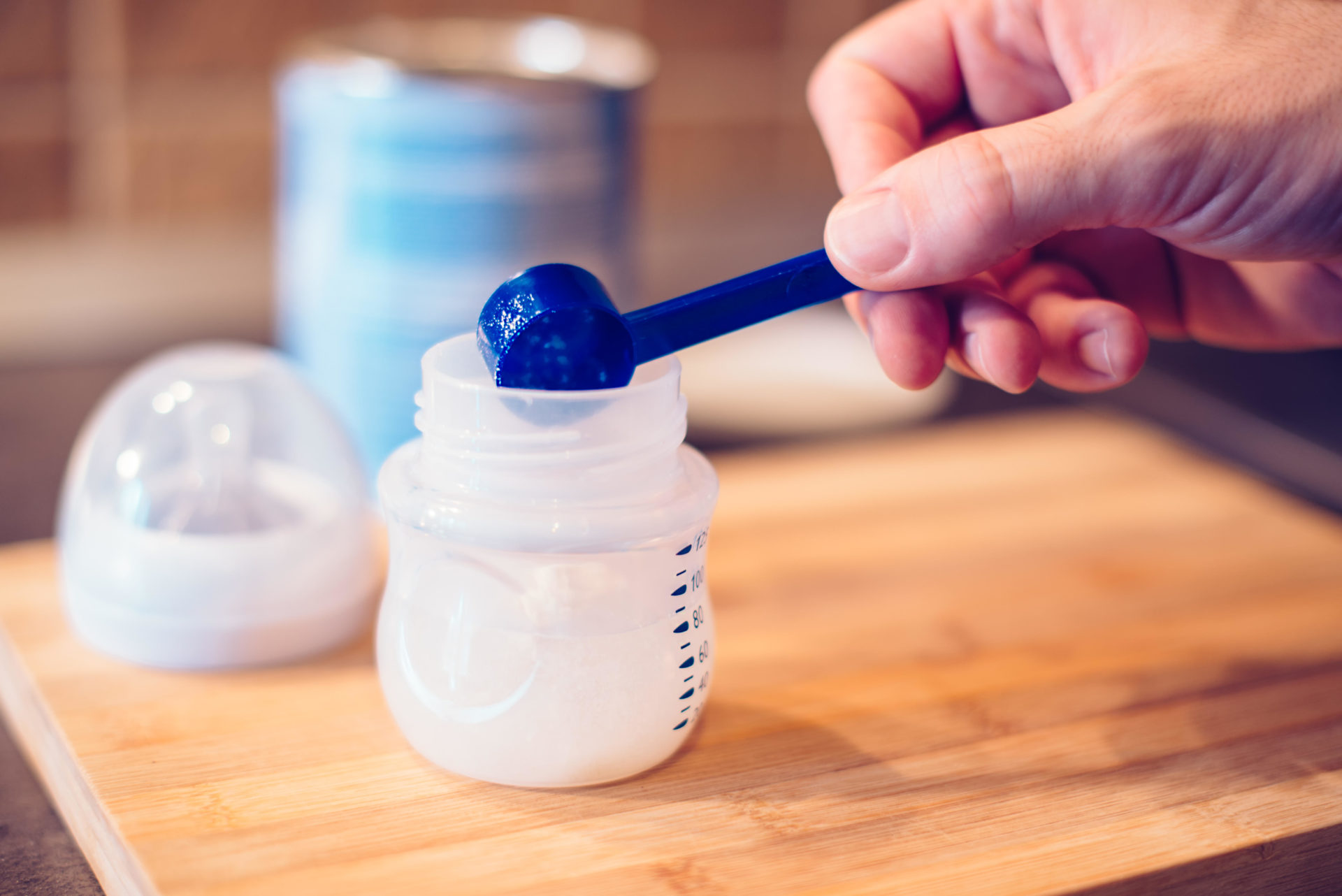 Father making baby formula in milk bottle for a newborn baby feed