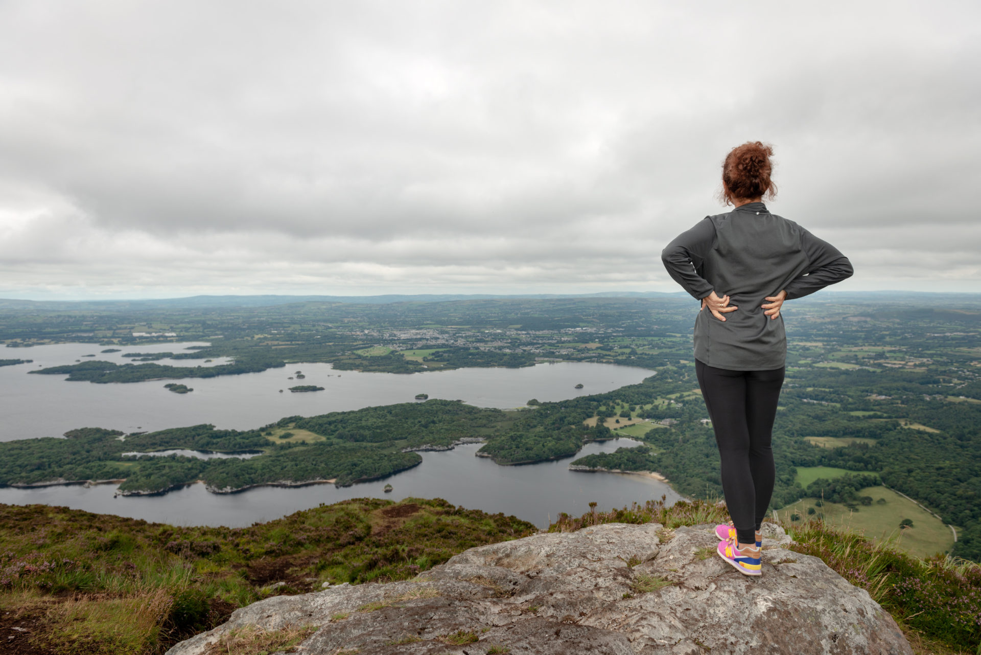 View to the Lakes of Killarney and Killarney Valley from Torc Mountain summit and a female hiker in Killarney National Park, County Kerry, Ireland