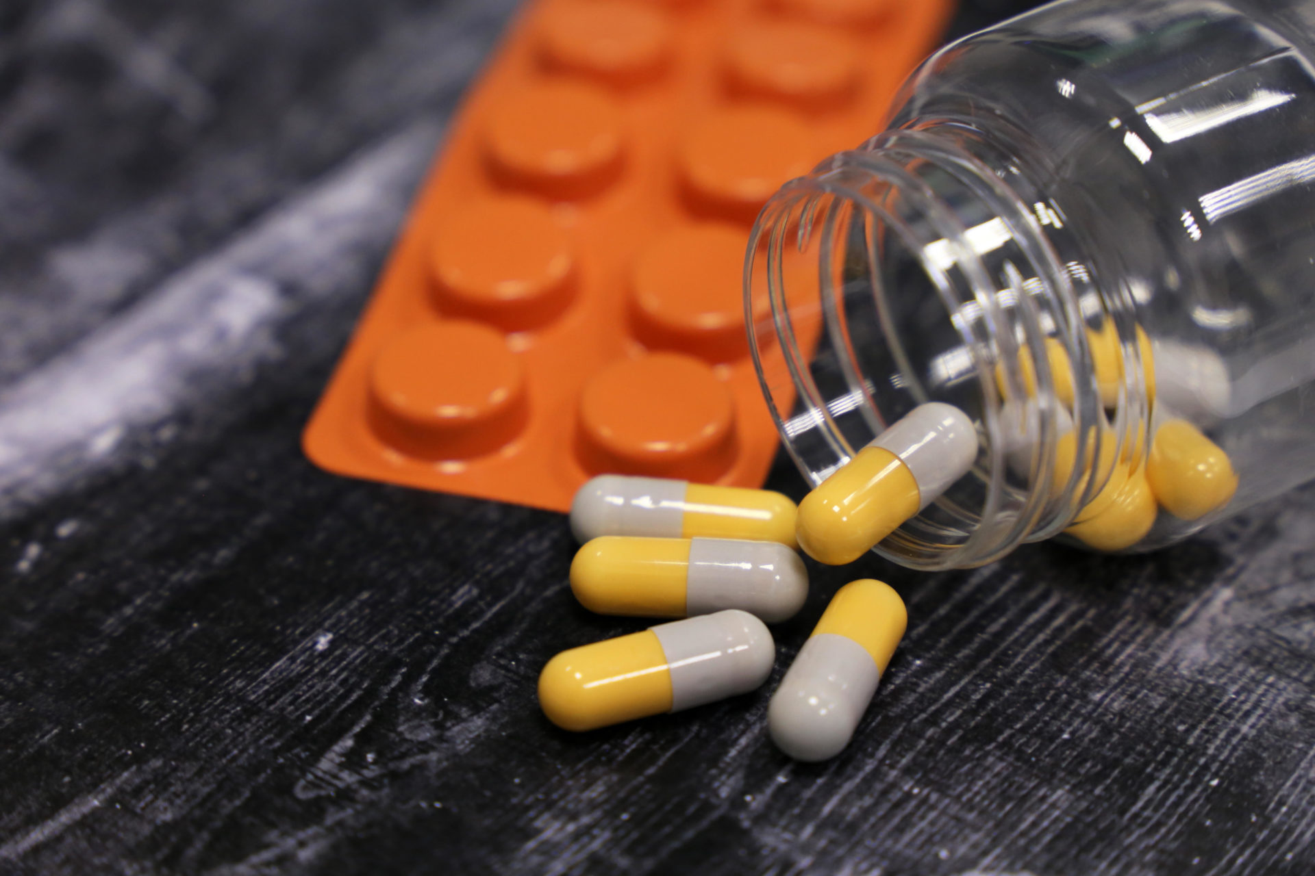 Capsules and blister pack of pills on dark wooden table.