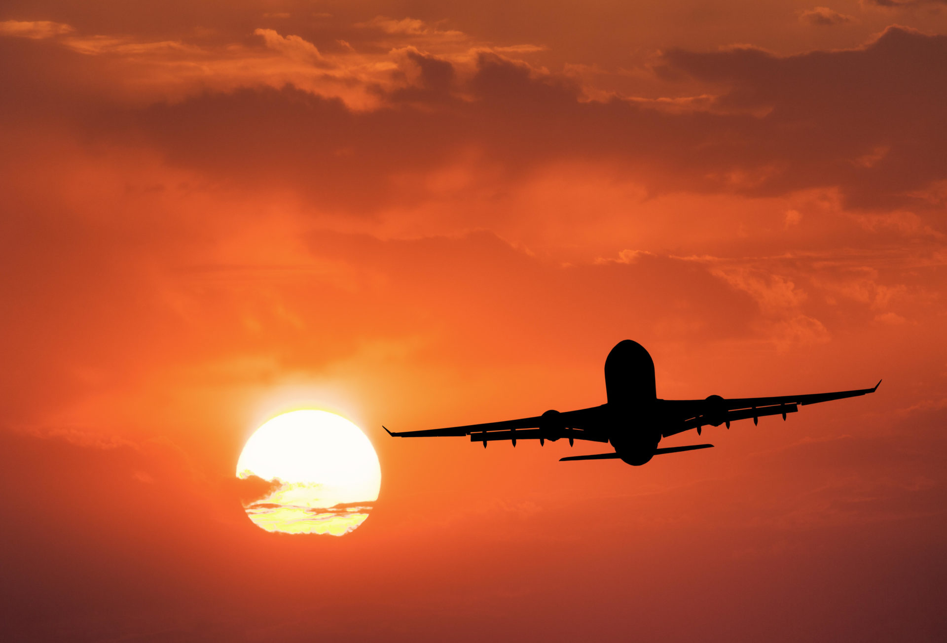 Silhouette of the aircraft and red sky with sun.