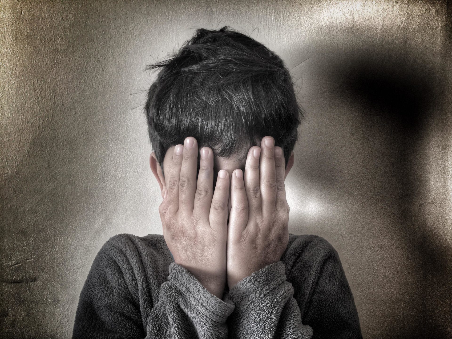 Boy hiding face with hands.