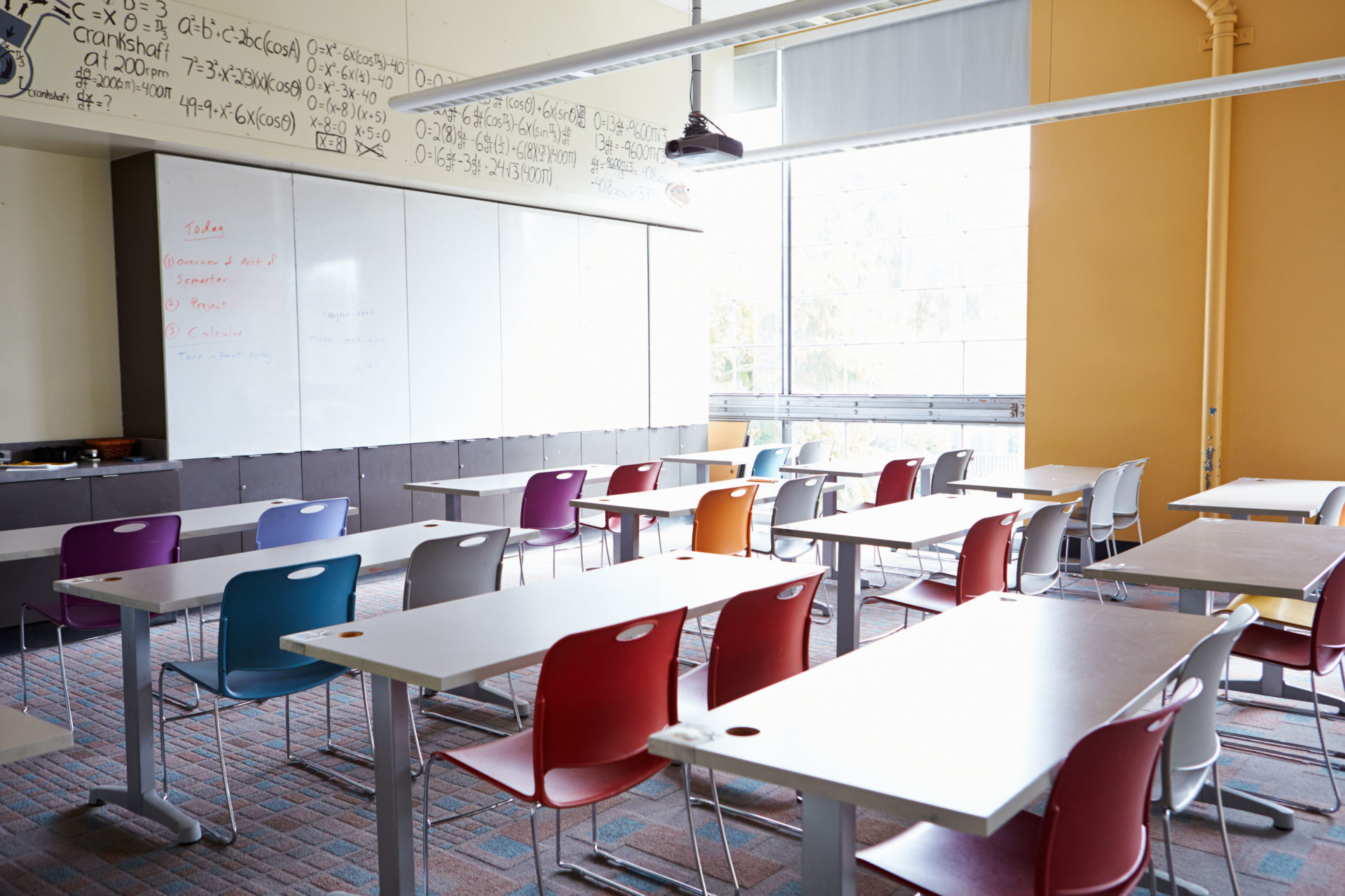 Empty School Classroom with chairs of different colours and a blank whiteboard.