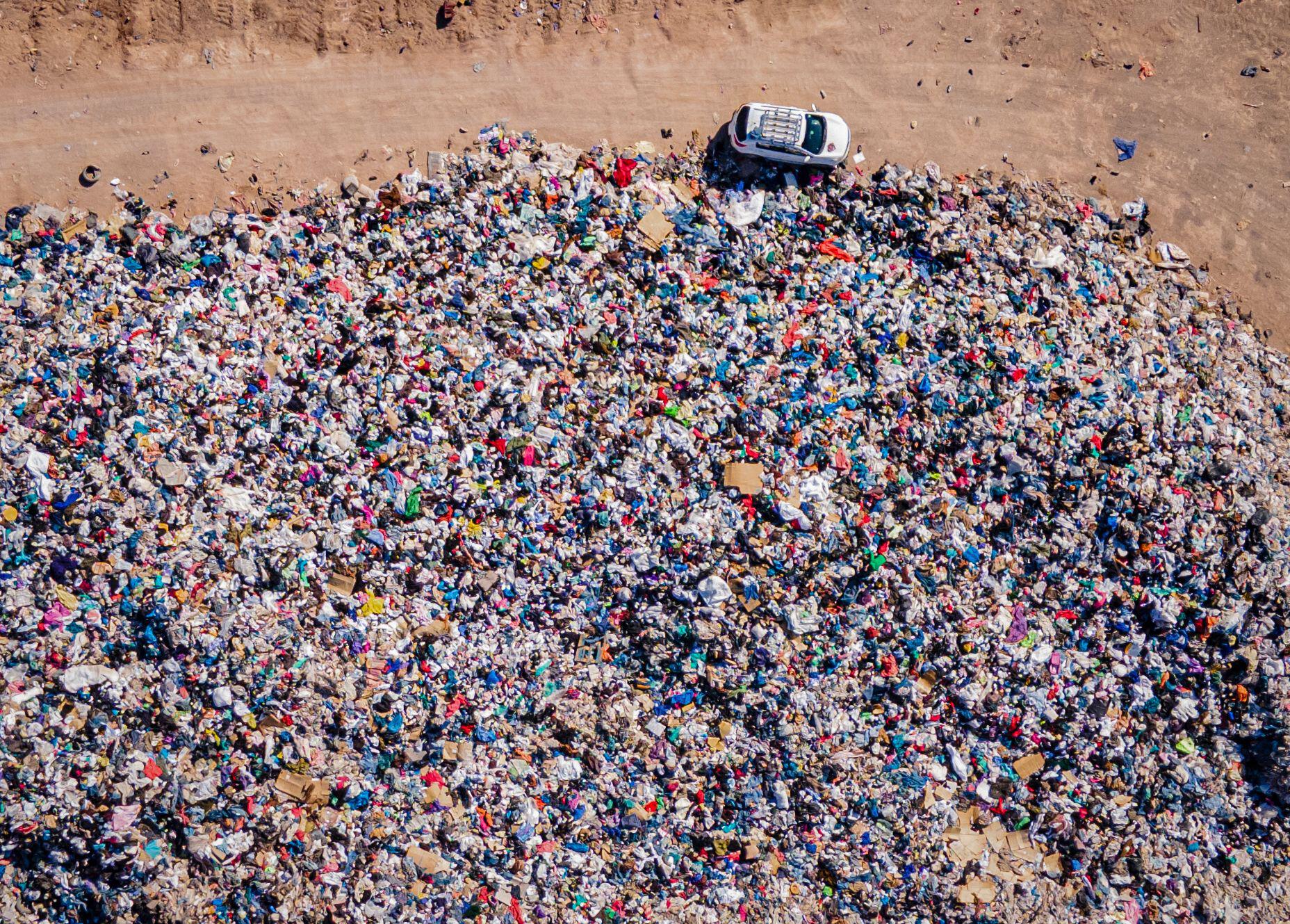 Used clothes sit in a landfill in the desert.