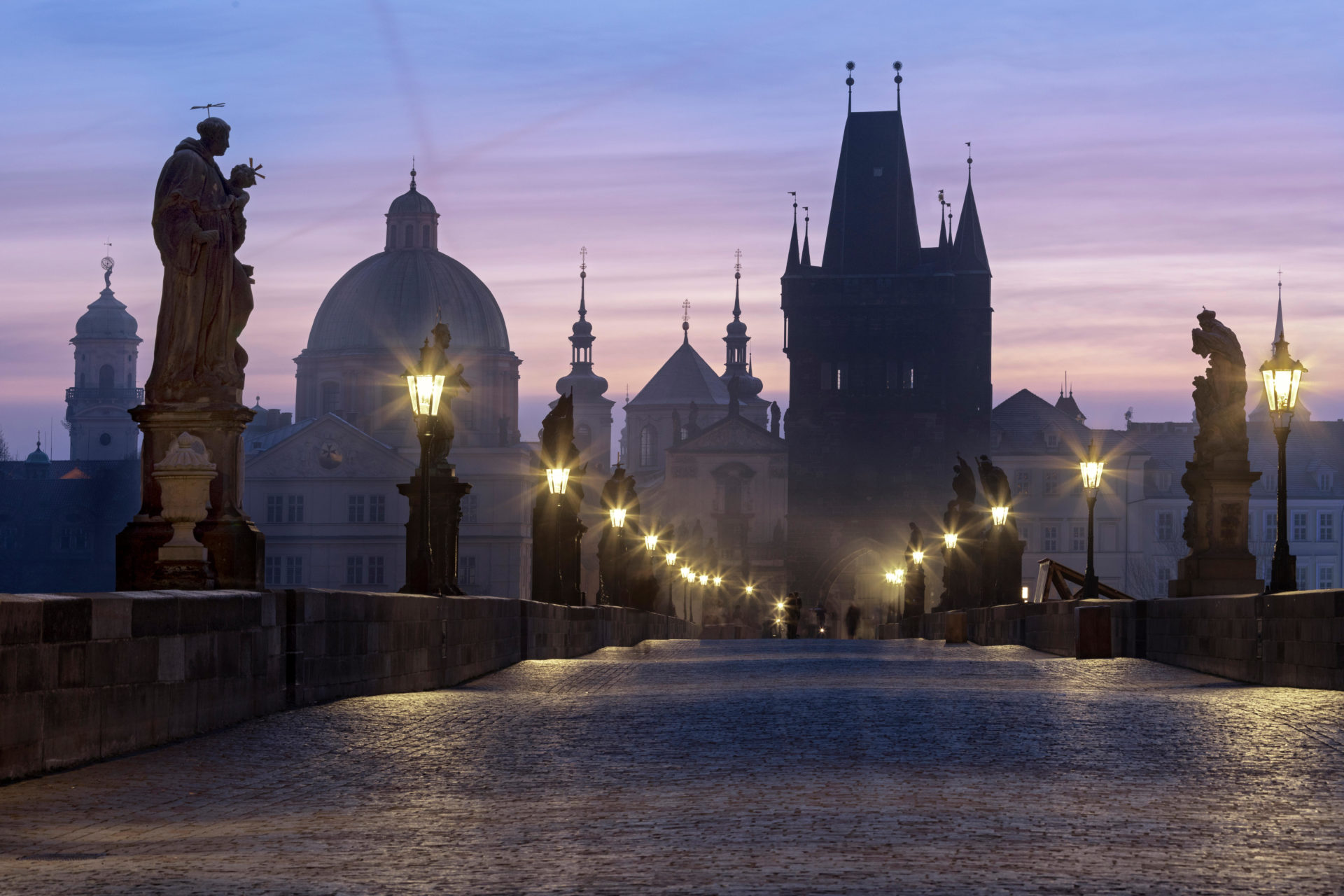 Street lanterns and old statues frame the historical buildings on Charles Bridge at dawn, UNESCO, Prague, Czech Republic
