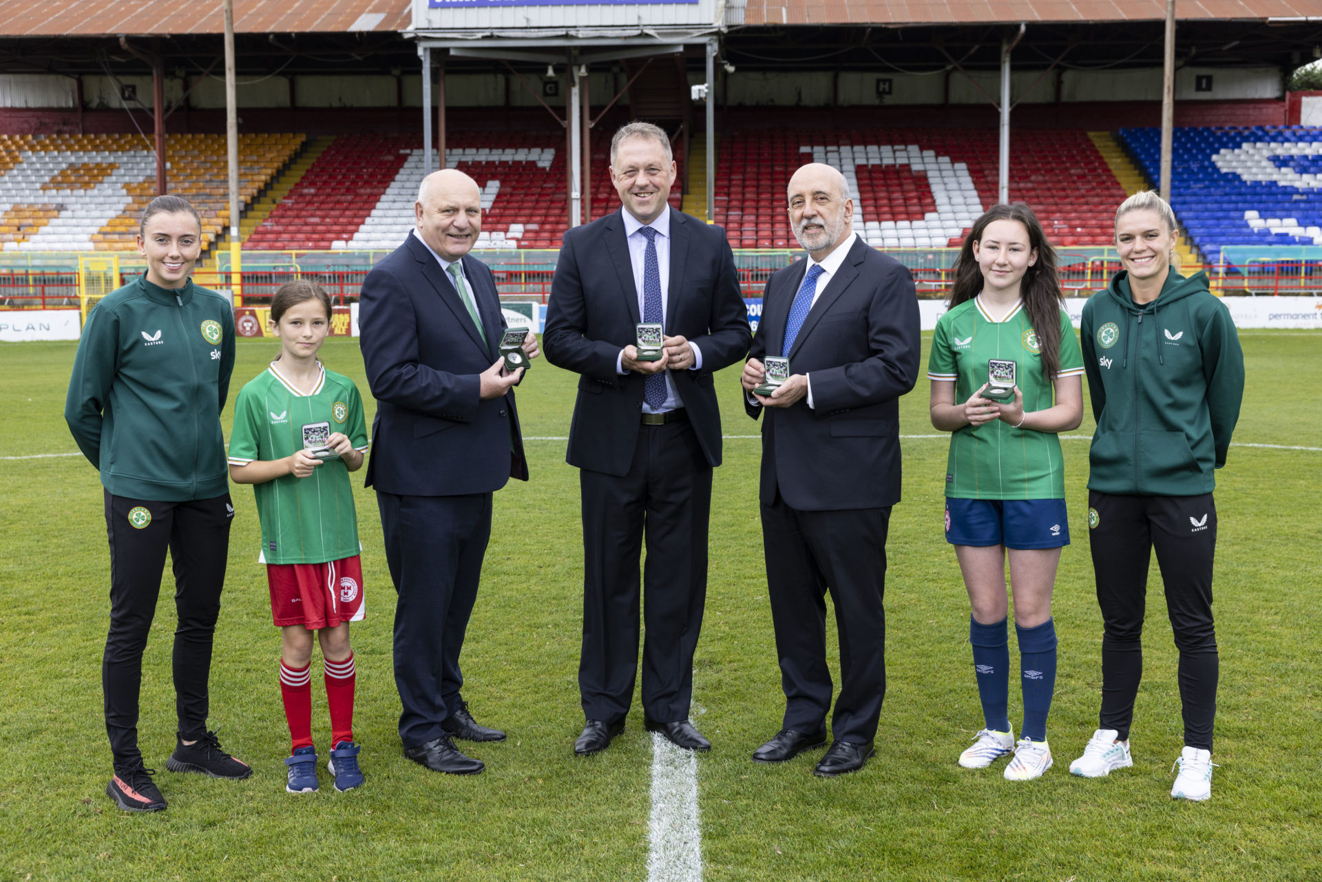 Ireland international player Abbie Larkin, Shelbourne youth player Daisy White, FAI President Gerry McAnaney, Minister for Sport and Physical Education, Thomas Byrne, Central Bank of Ireland Governor Gabriel Makhlouf, Shelbourne youth player Ellie O’Mahony, and Ireland international Jamie Finn launching the coin in Tolka Park