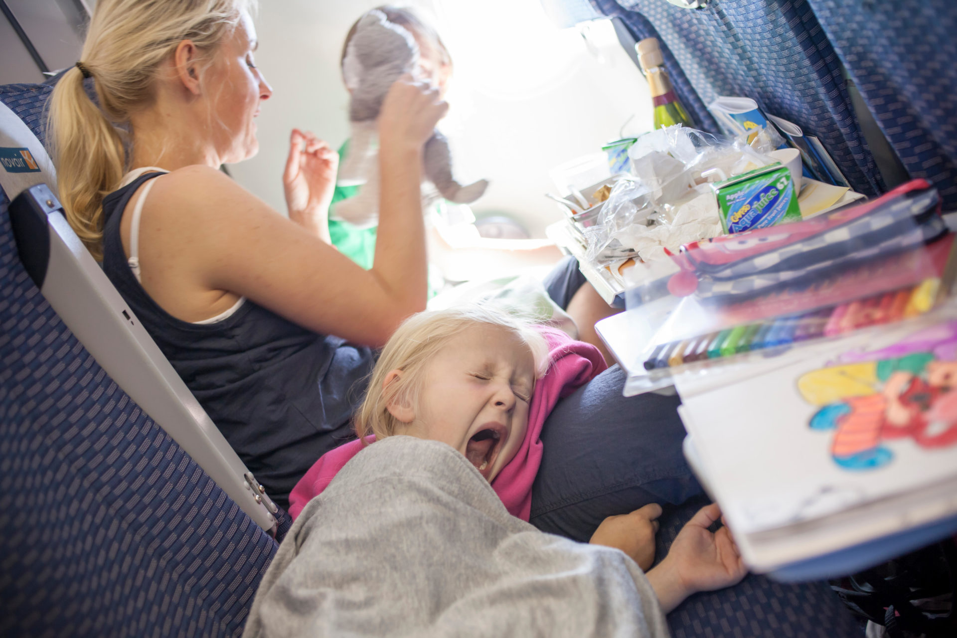 Woman with yawning child on plane 