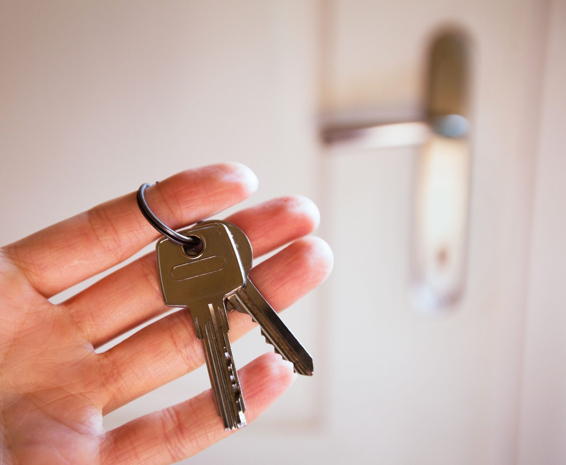 A person at an apartment door with keys in their hand