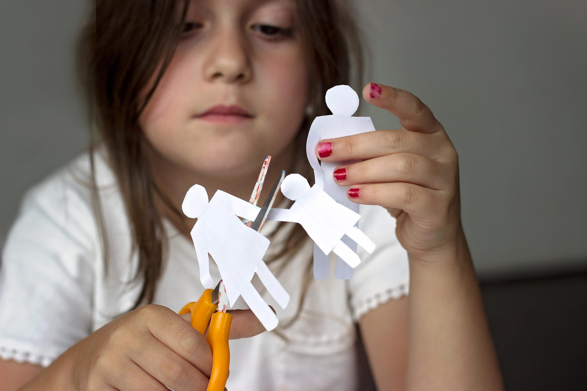 Little girl with paper family and scissors 