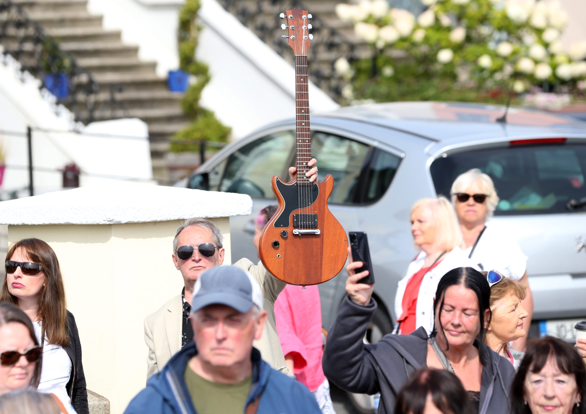 A man holds a guitar in the air Sinéad O’Connor's former home in Bray on the morning of her funeral