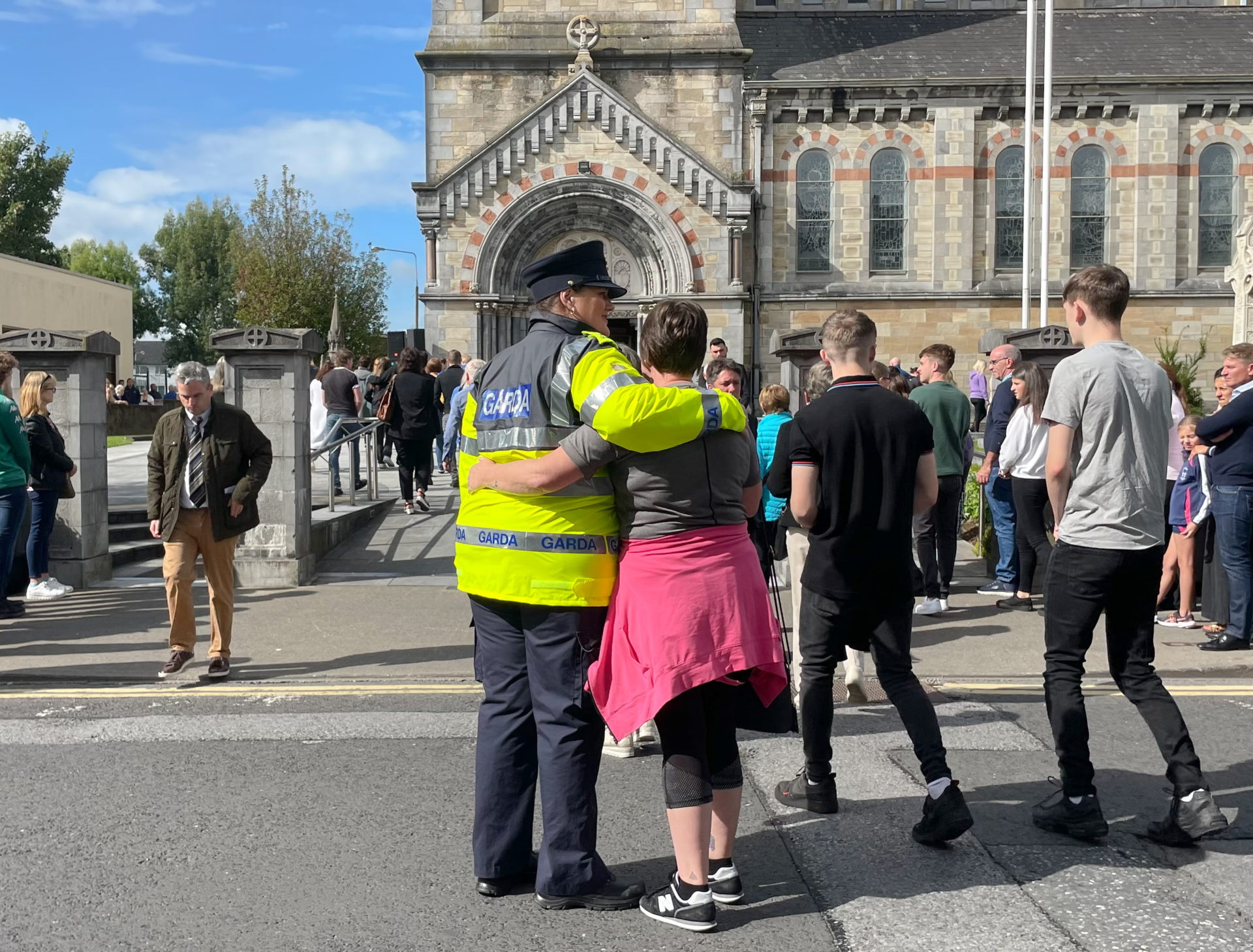 A Garda and a mourner embrace outside St Peter and Paul's Church, Clonmel, before the funeral of brother and sister Luke and Grace McSweeney