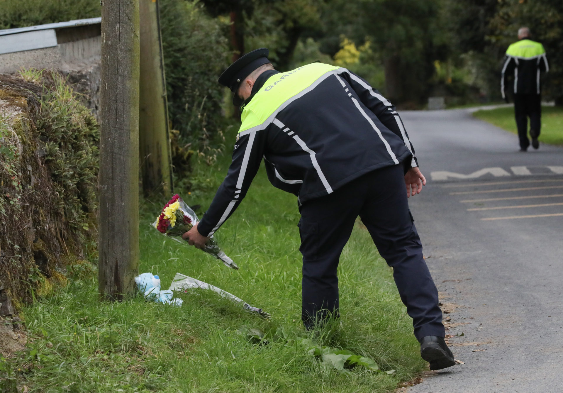 30/08/2023 Tipperary, Ireland. A member of An Garda Siochana places flowers given by the public near the scene of the crash in the Windmill Knockbulloge area of Cashel, Co. Tipperary, which claimed the lives of three people last night. Tom Reilly (48), his wife Bridge Reilly (45) and their grandson Tommy Reilly (3) died after the car they were travelling in hit a wall shortly before 9pm yesterday. Two further passengers have been hospitalised following the incident. Photograph: Sasko Lazarov / © RollingNews.ie