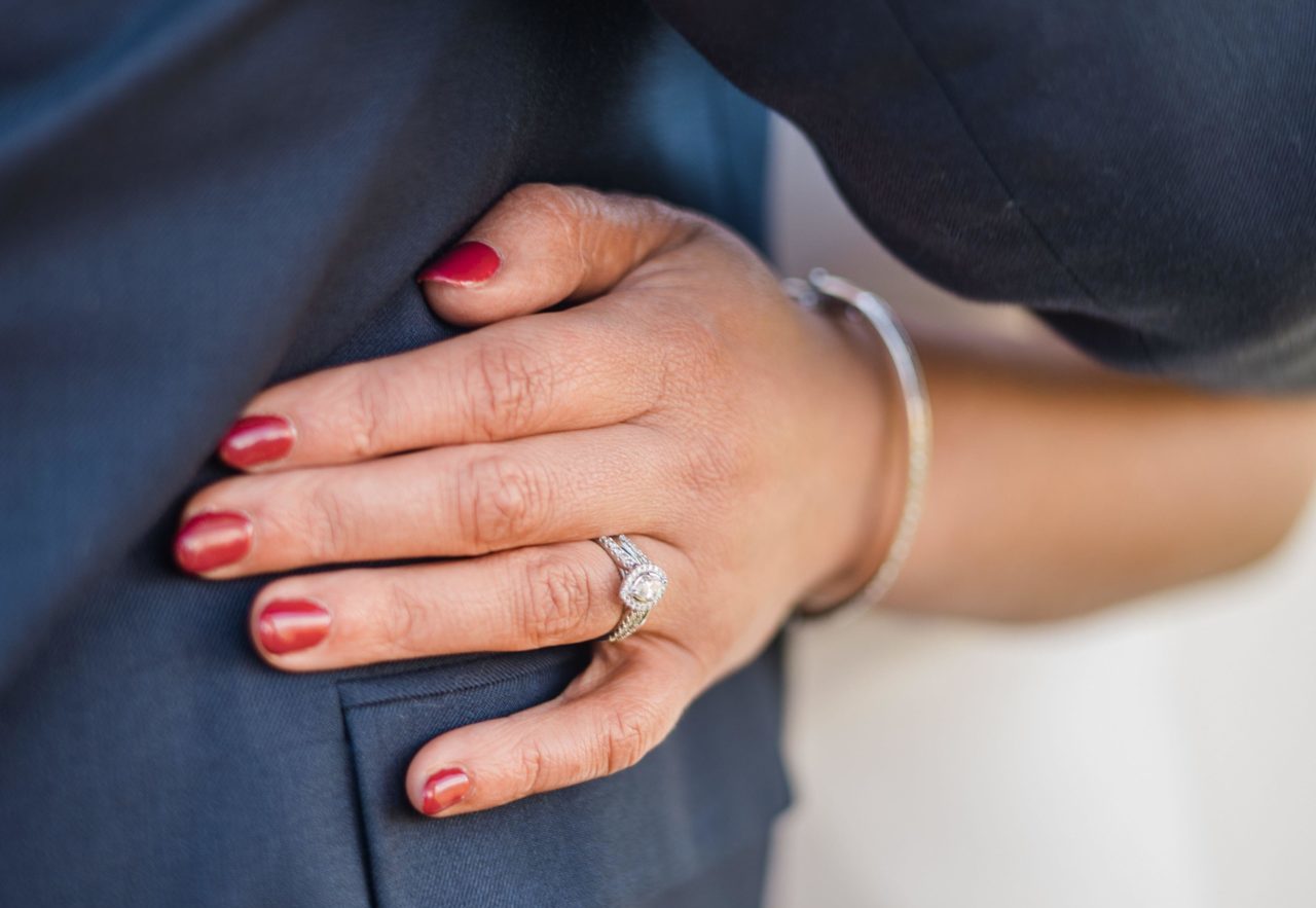 2RME765 Bride's hand and ring gleam in an emotional wedding embrace