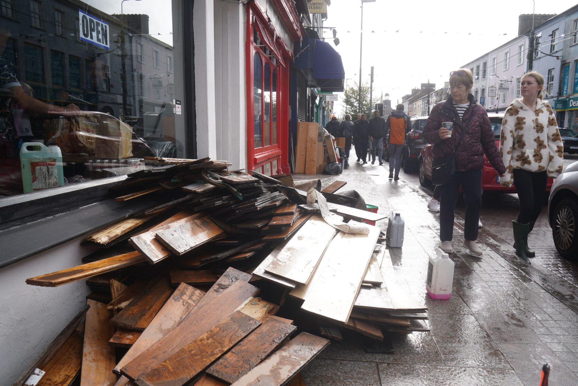 People walk past damaged shops on Main street in Midleton