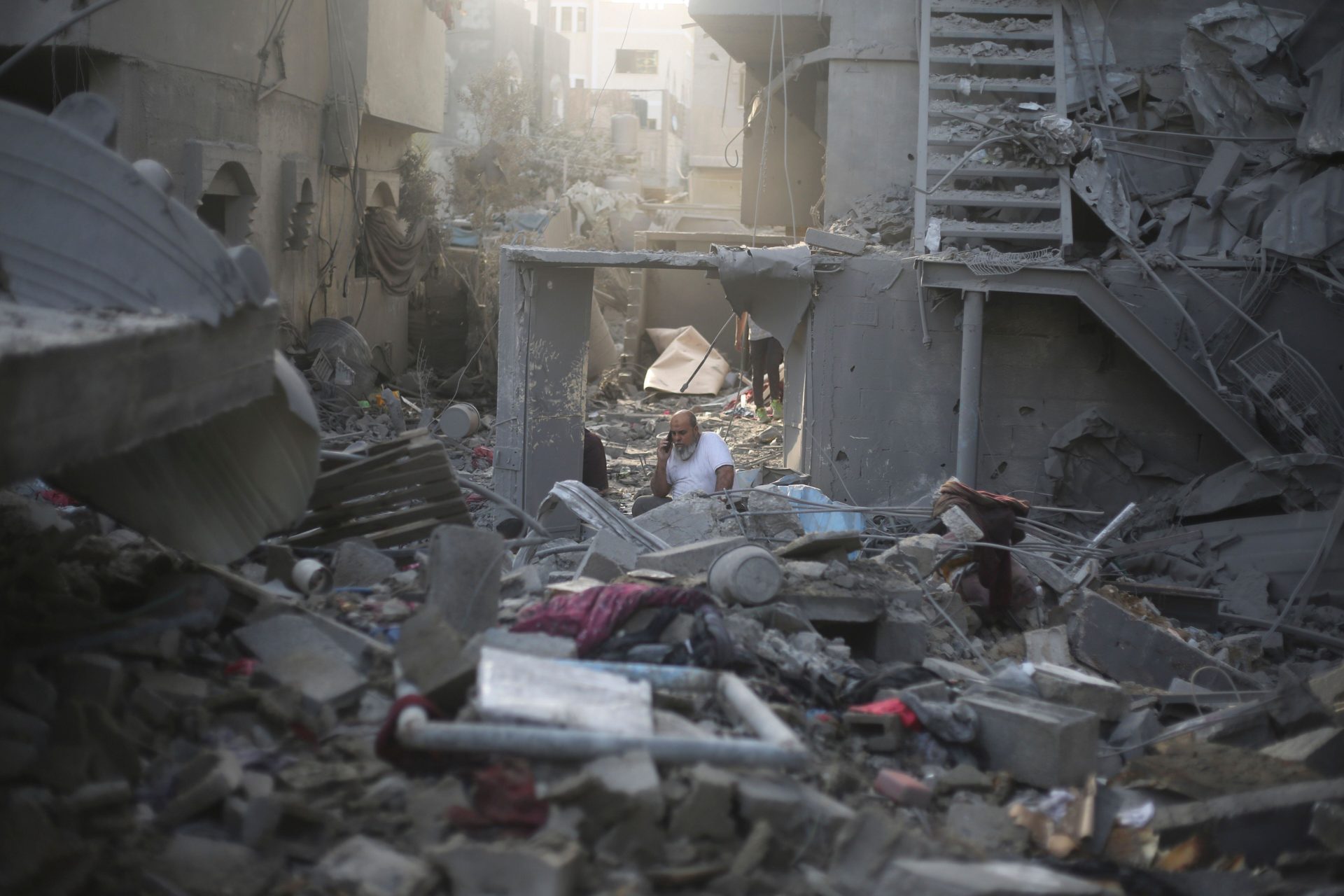A man talks on the phone by buildings destroyed in the Israeli bombardment of the Gaza Strip in Rafah