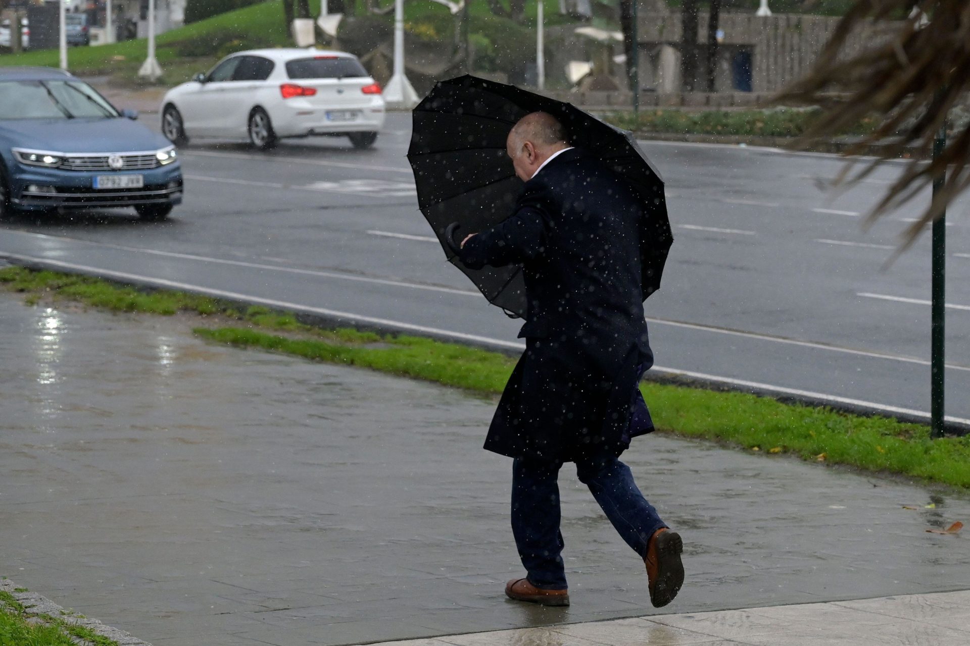 A man with an umbrella tries to take shelter from the wind in a red weather warning