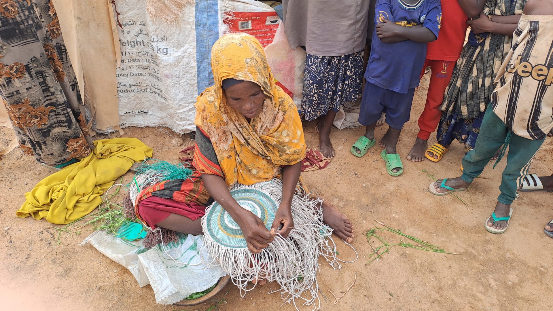 A woman at a camp for Internally Displaced People in Dolo, Somalia. She makes baskets, which takes her three days, and sells them for $5