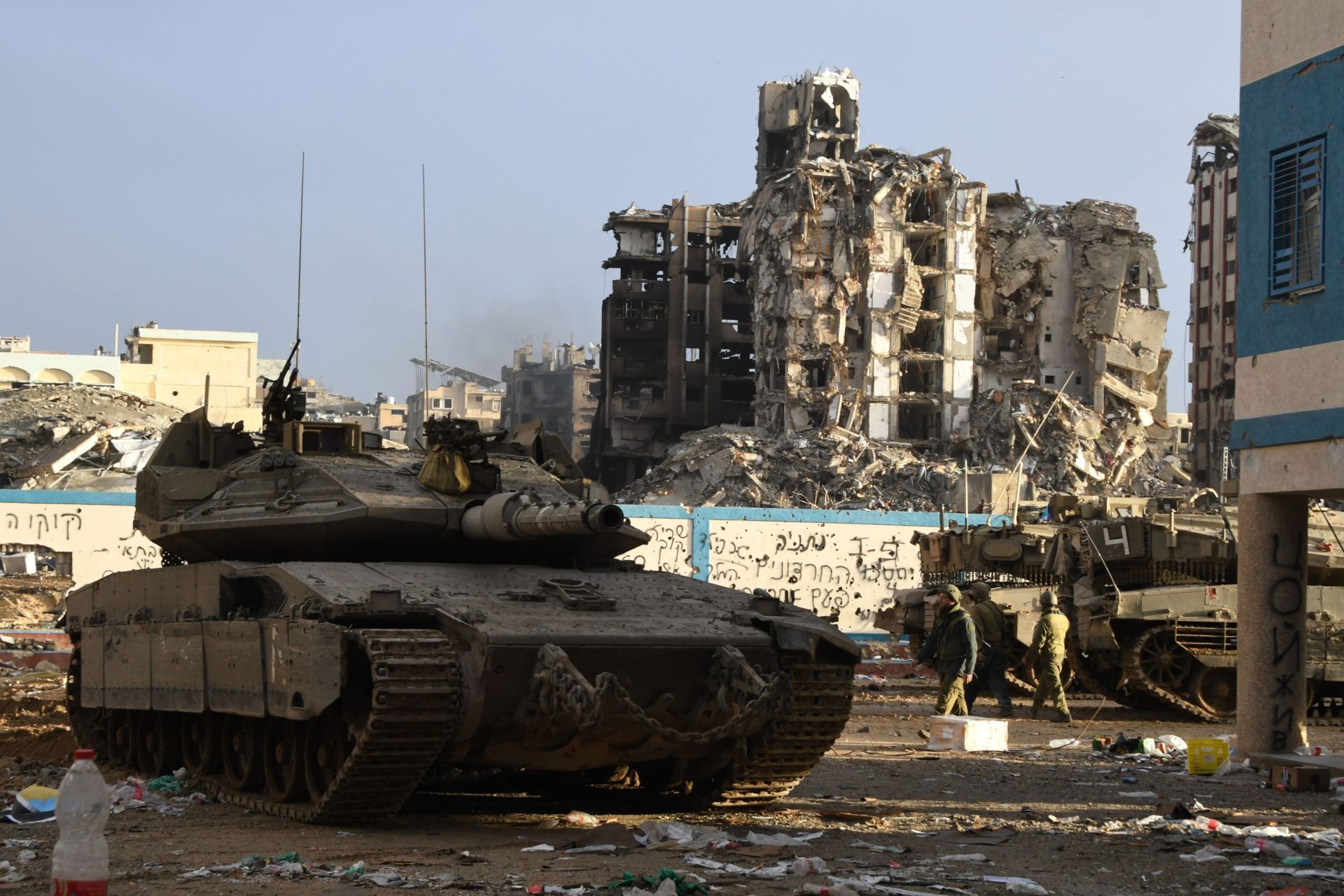 Israeli Defence Forces advancing in the Gaza Strip in a tank with a destroyed building prominent in the background
