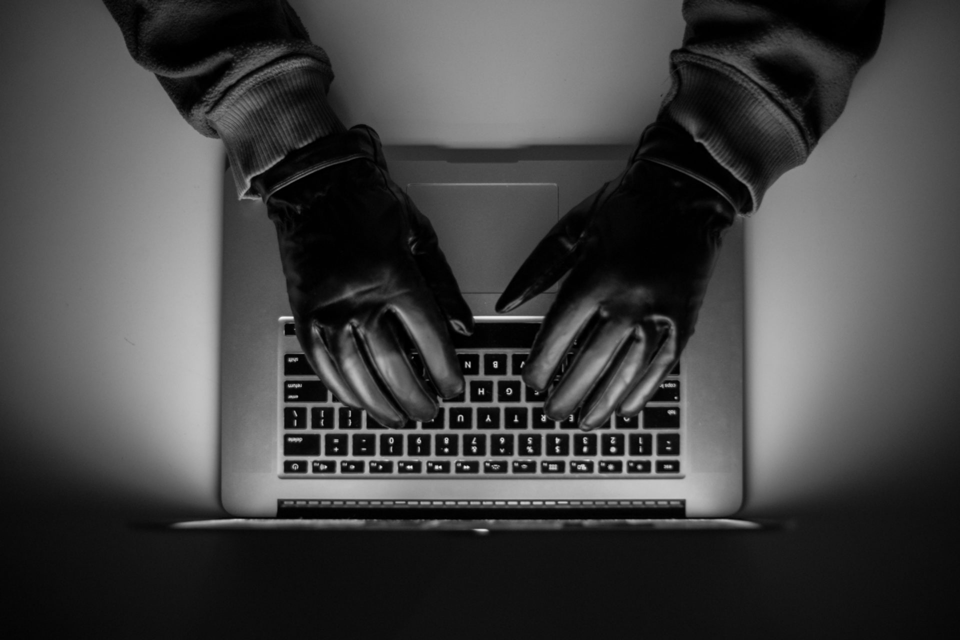 Online crime takes place as someone wearing black gloves types on laptop. Image: Hajrudin Hodzic / Alamy Stock Photo