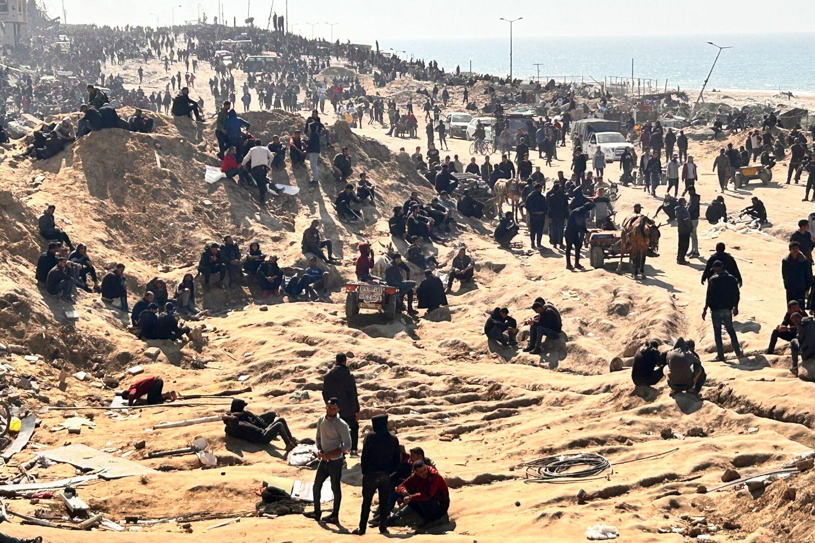 Palestinians wait for humanitarian aid on a beachfront in Gaza City