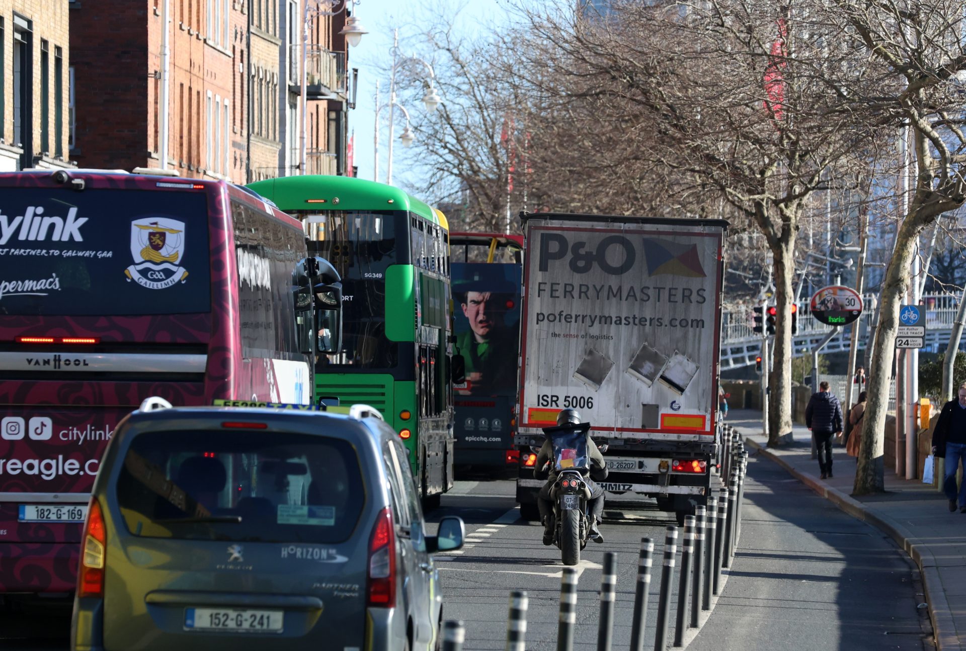 Cars and heavy articulated trucks on Bachelor's Walk Quay in Dublin city, 12-2-24.