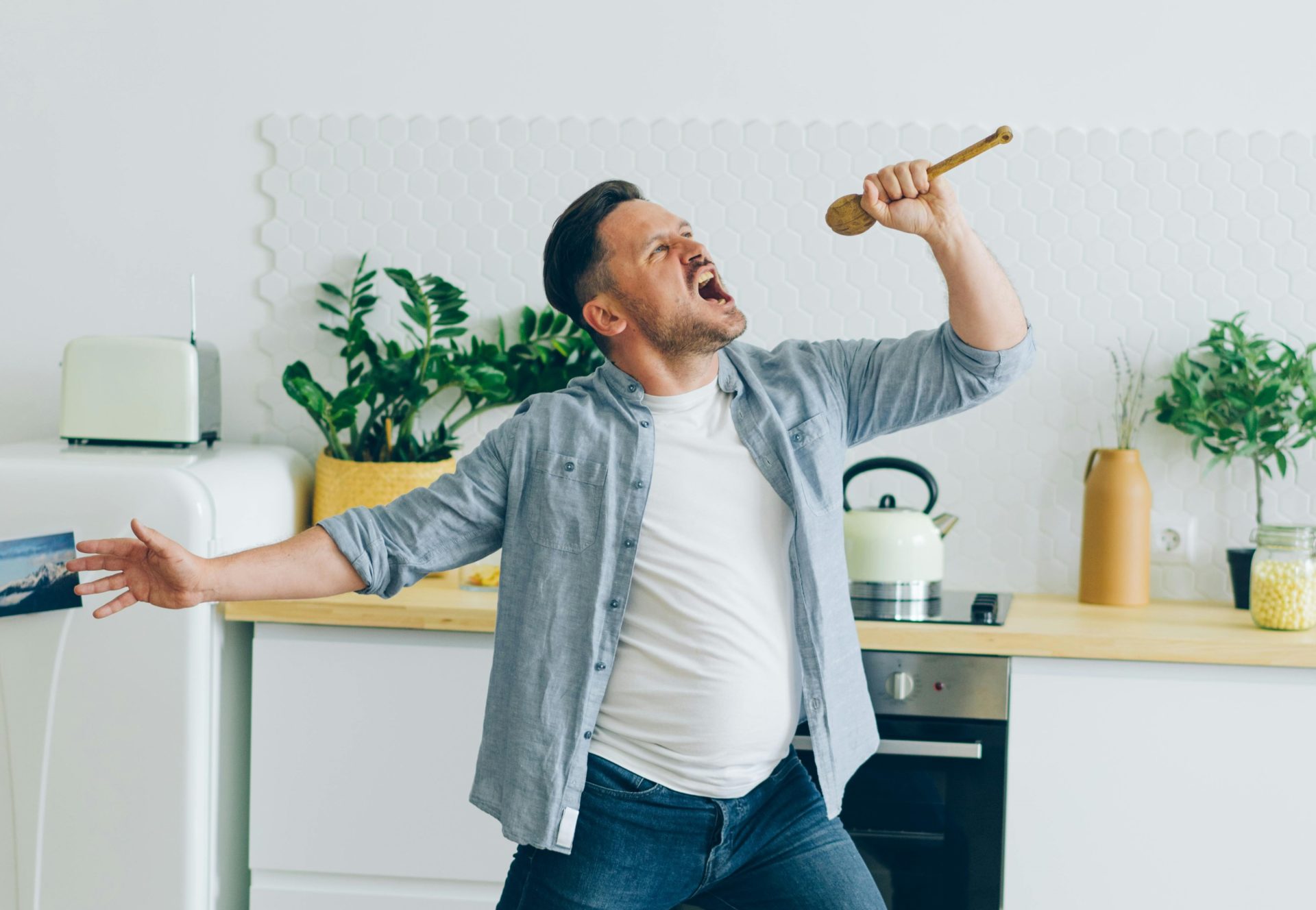Man singing using a wooden spoon as a pretend microphone. Image: Pexels