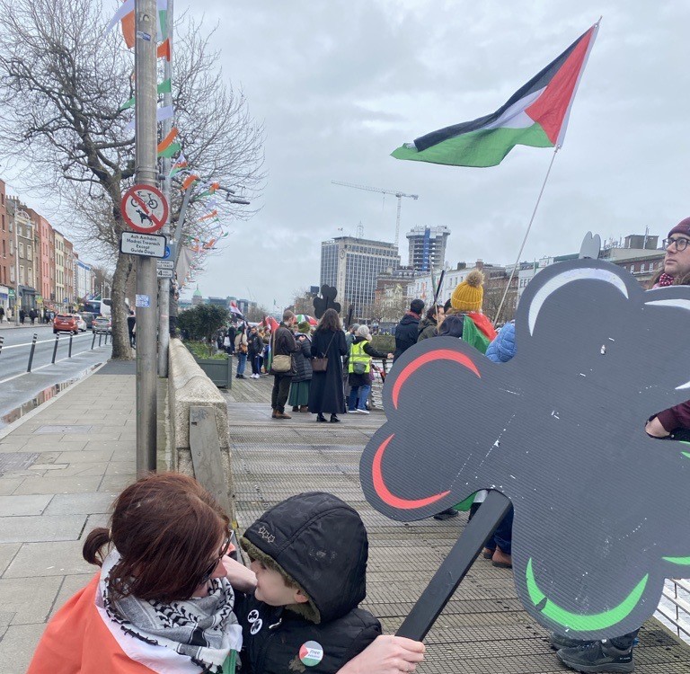 Protestors by the Liffey river with a black shamrock lined with the colours of the flags of Palestine, 16/03/2024. Image: Marése O'Sullivan