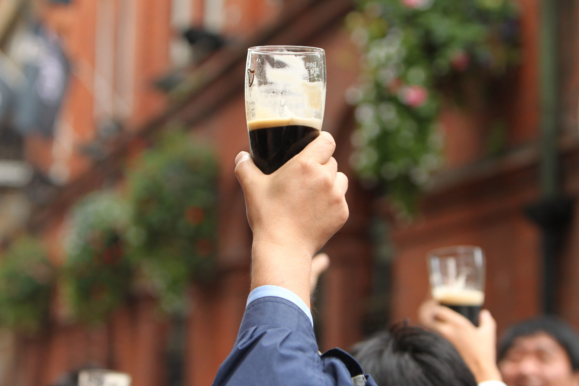 A hand holds a pint of Guinness in the air