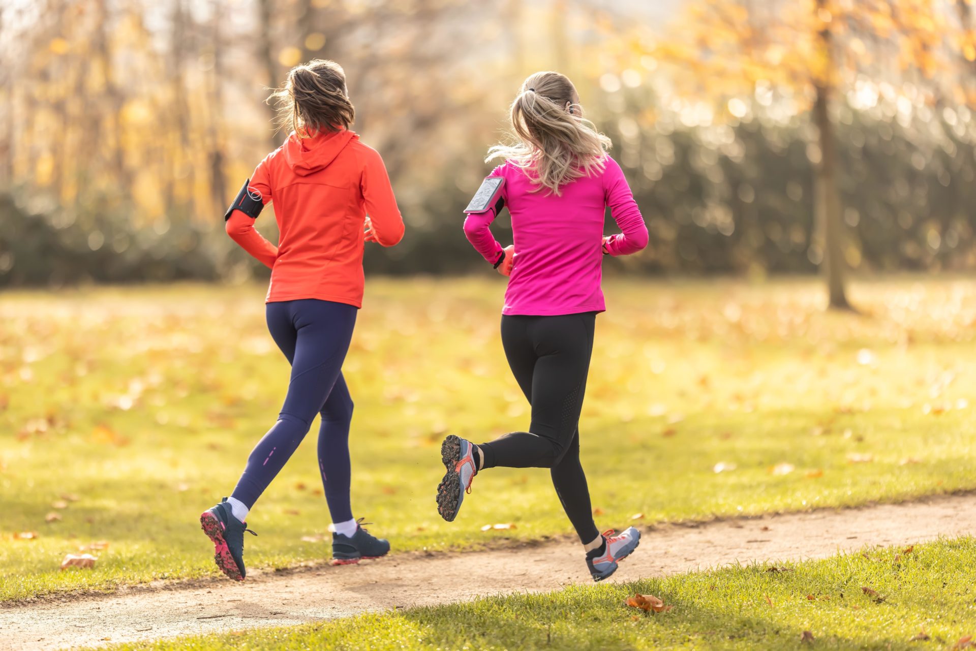 #GirlRun: Two young fitness women running in the autumn park.