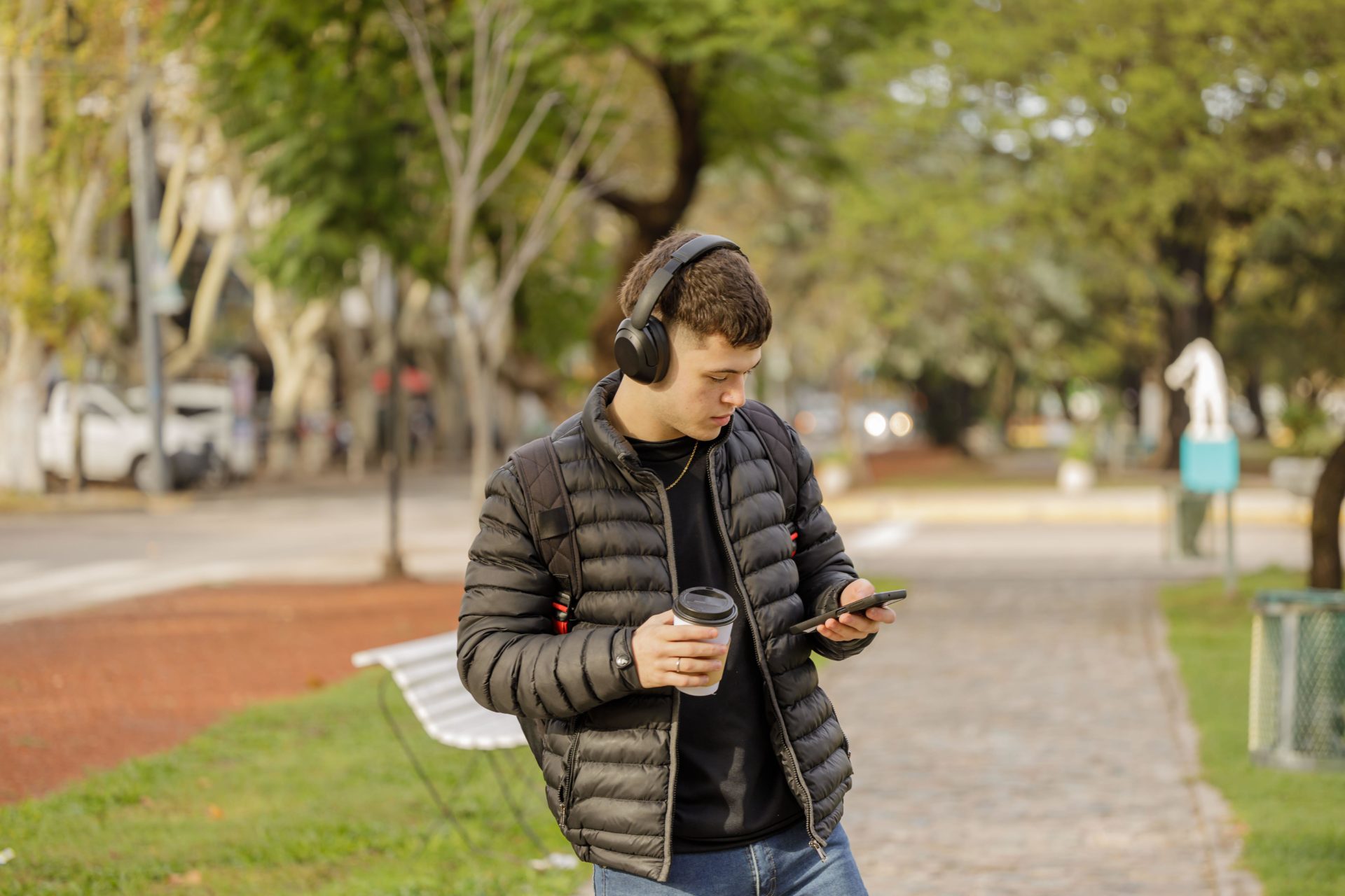 A boy with headphones uses his mobile phone while walking, 20-5-23. 