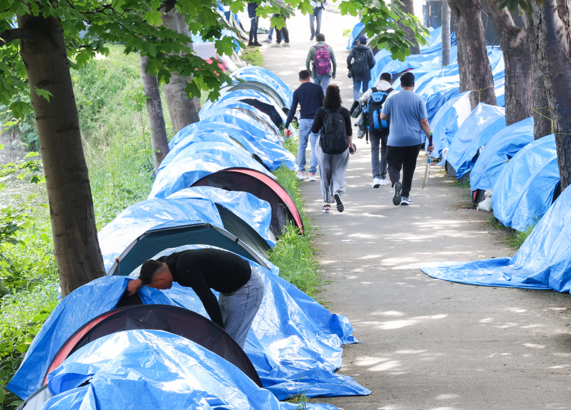 Members of the public pass tents belonging to asylum seekers along the Grand Canal, as news reports indicate the number of tents has now increased to above 100. Photograph: Sasko Lazarov / © RollingNews.ie