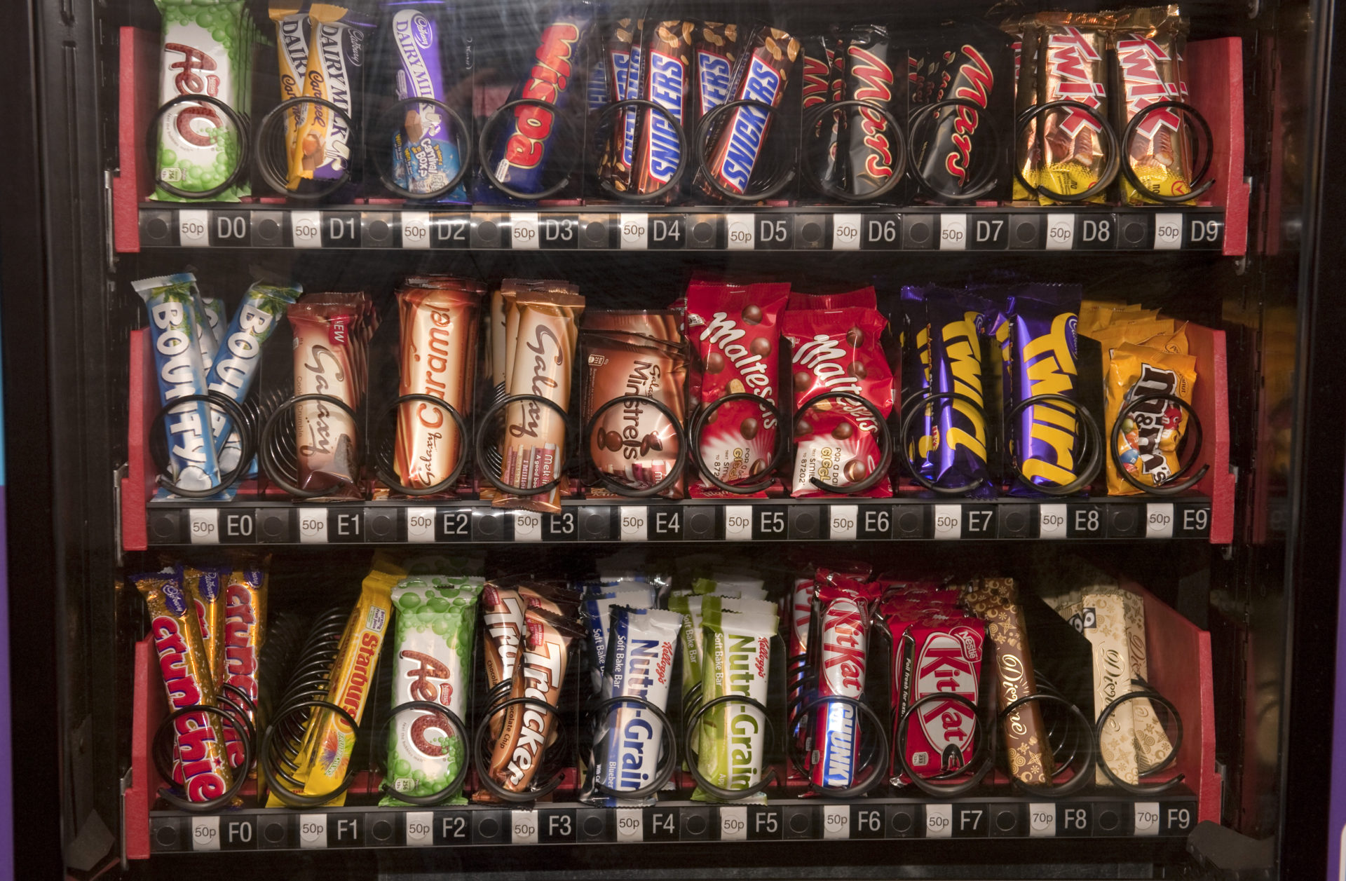 A close up of chocolate bars in a vending machine - chocolate bars are often subject to 'shrinkflation'