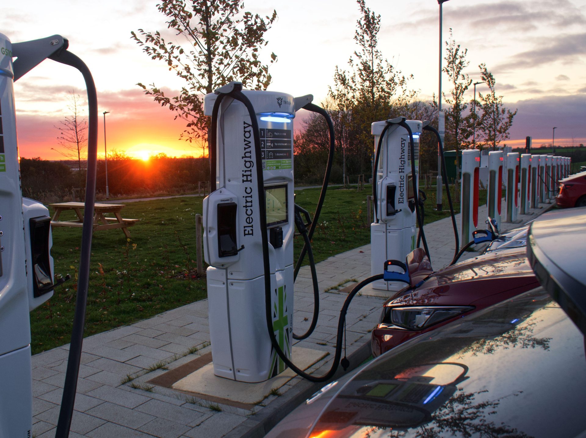 Electric vehicles charging at sunset at fast motorway chargers, 21-11-21.