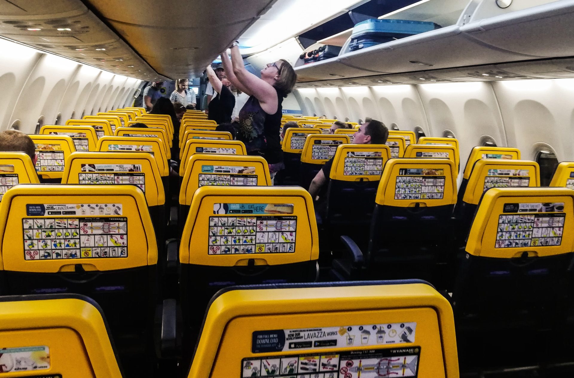 A passenger places hand luggage in the overhead bin on a Ryanair aircraft, 5-6-19.