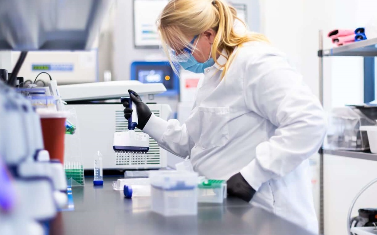 A scientist in a lab filling containers.