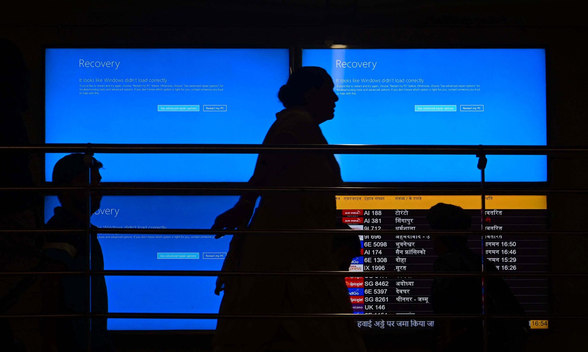 Person walking by Microsoft 'blue screen of death' on multiple screens. Image: Sipa USA / Alamy Stock Photo