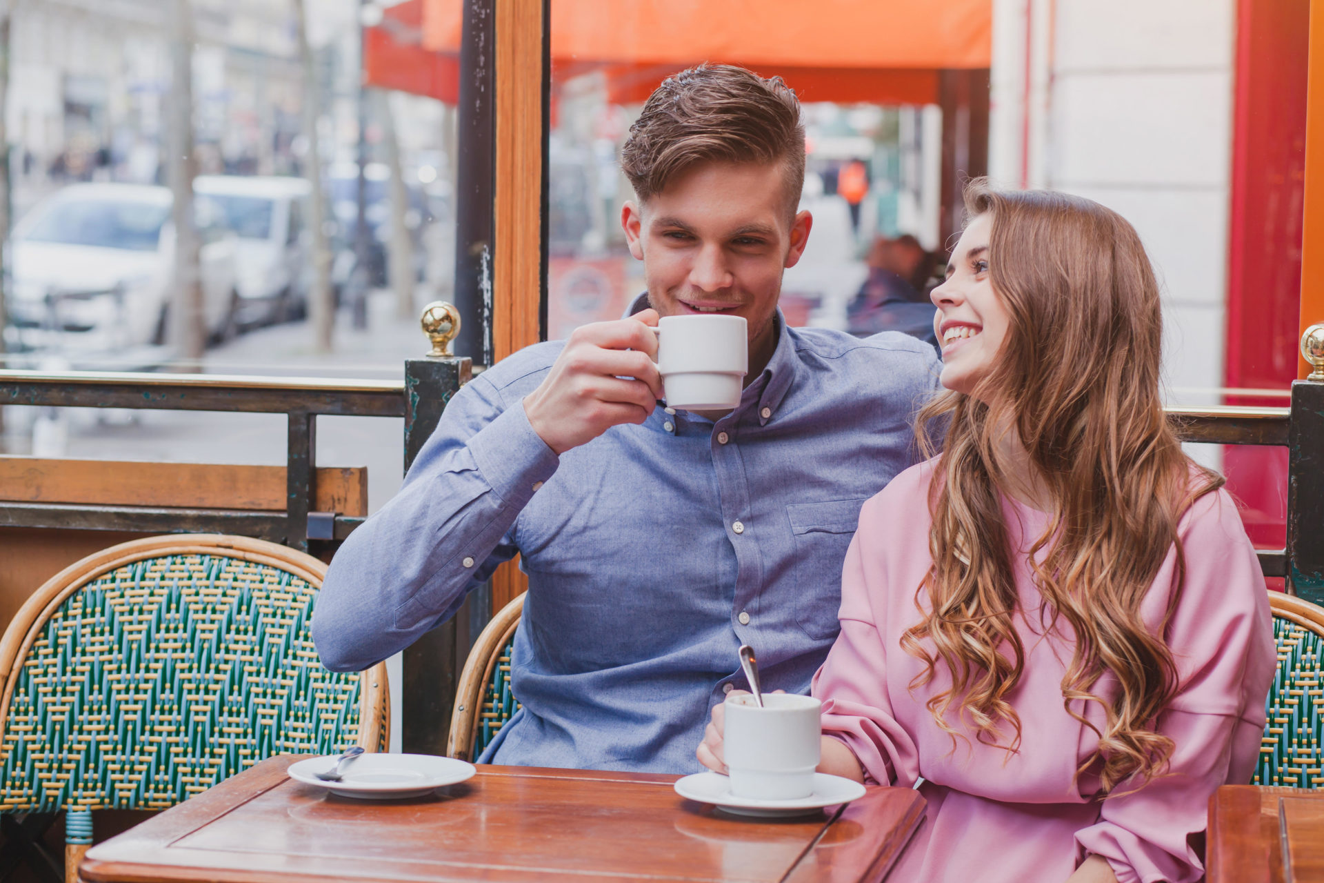 young happy couple drinking coffee and laughing in cafe in Europe, dating, good positive moments