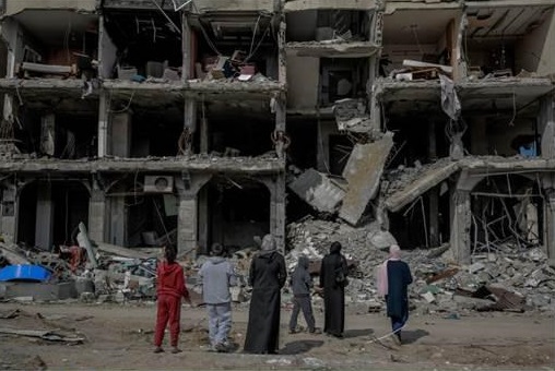 A family looks at an apartment block destroyed by a missile strike in Gaza City, 21-2-24. 