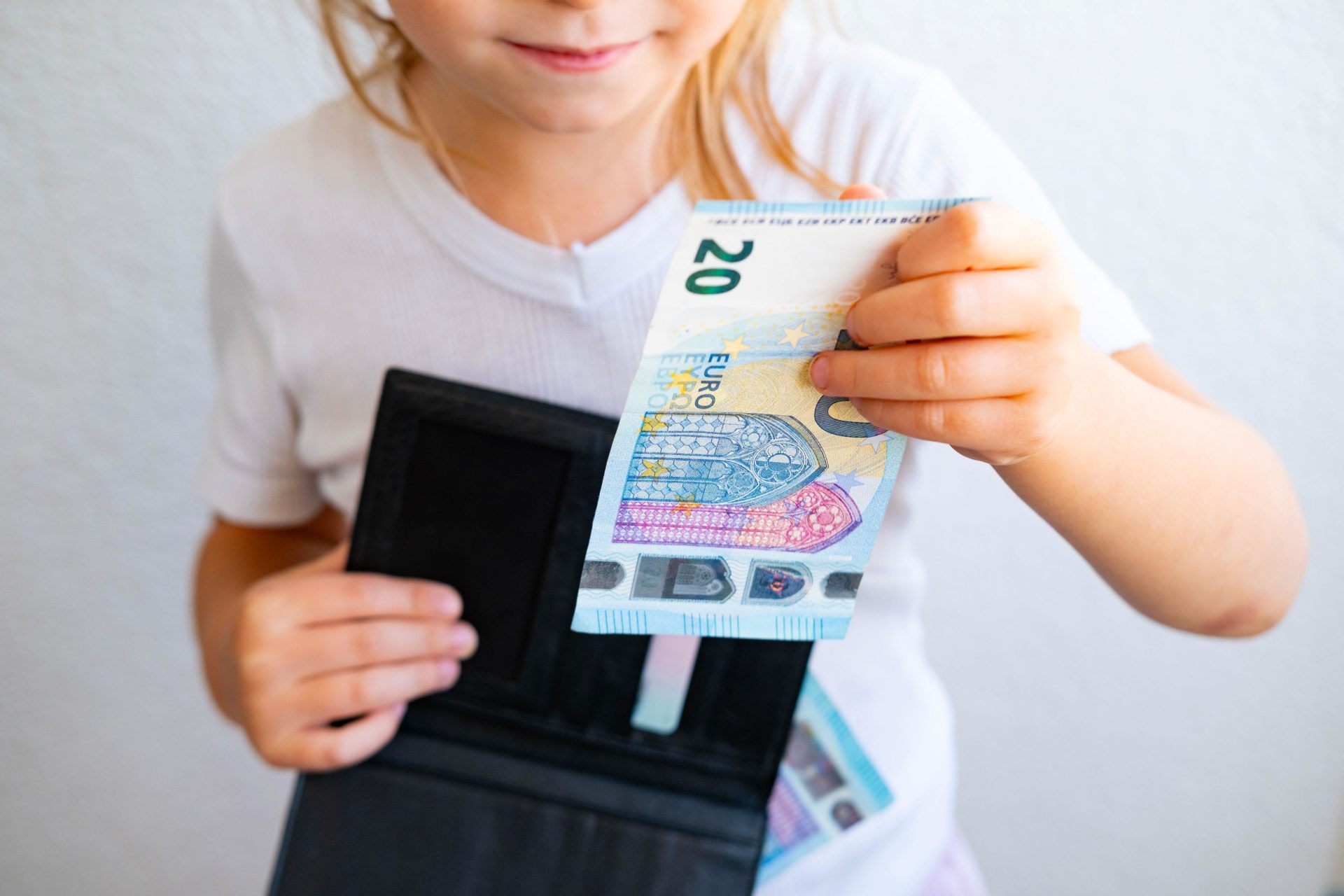 A child holding money and a black wallet