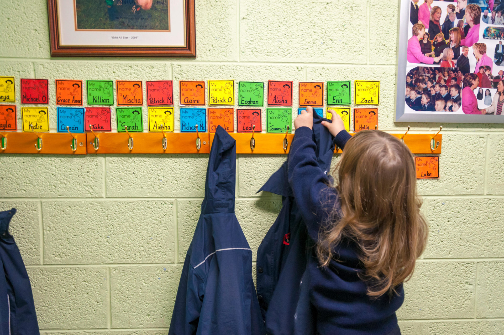 Child hangs up her coat on a named hanger at her school