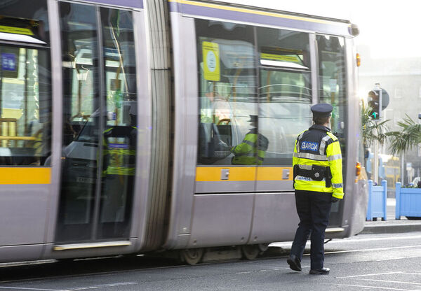 A Garda standing next to a Luas.