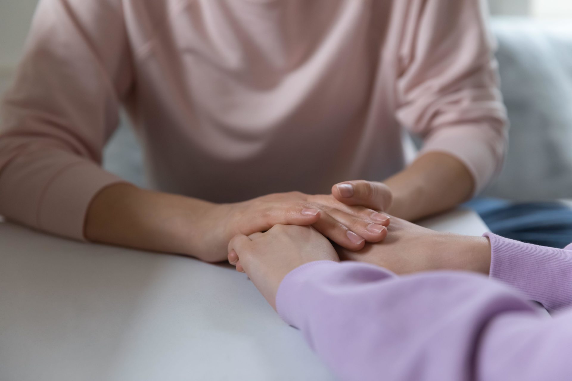 A parent holds hands with a child across a table.