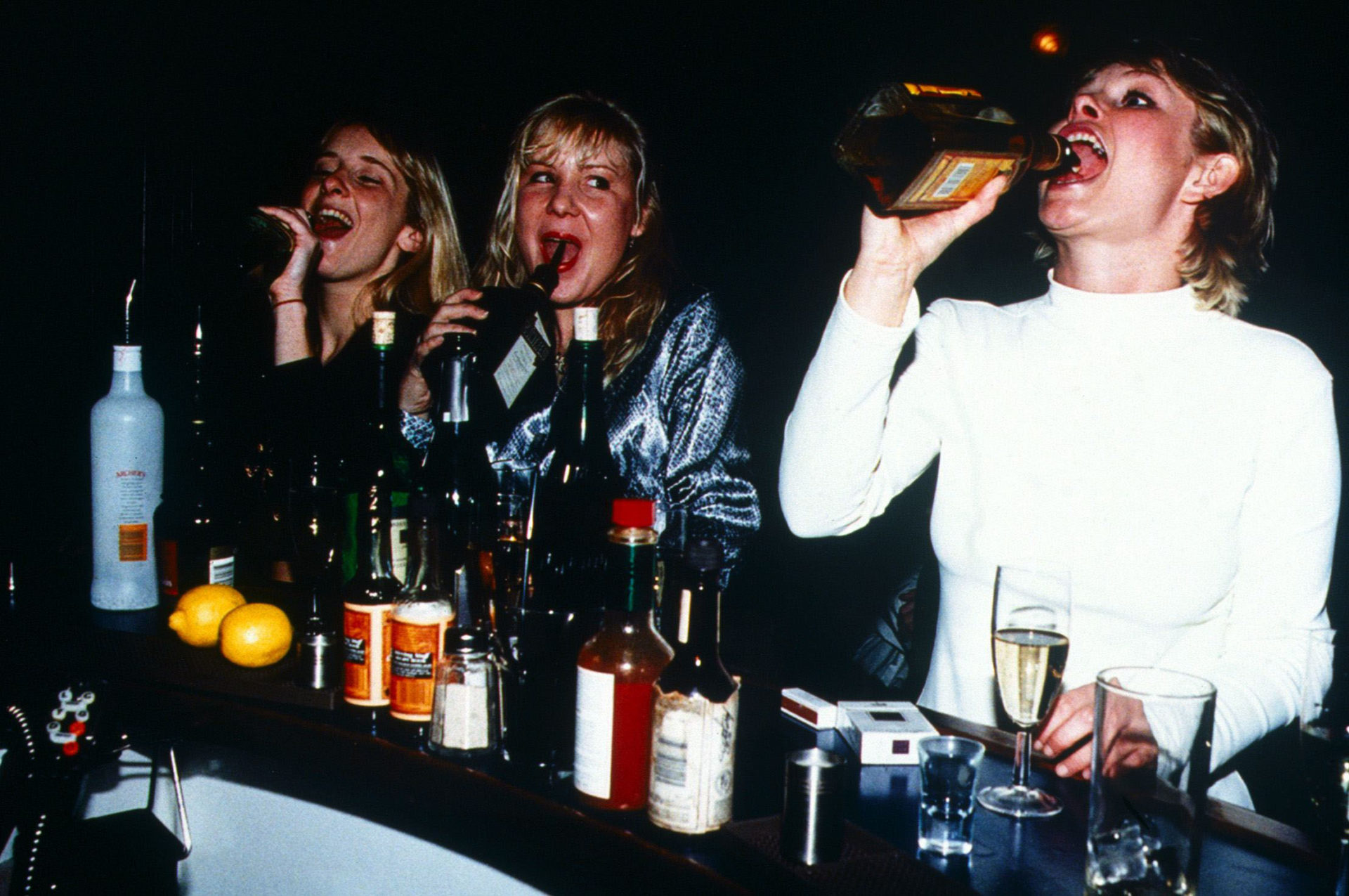 Young Women drinking straight from the bottle in a Bar January 1996 Girls driking alcohol tequila cointreau getting drunk laughing smiling having fun ladette culture white dress drinking alcohol drunk womens liberation 24 01 1996 womenpixs0405