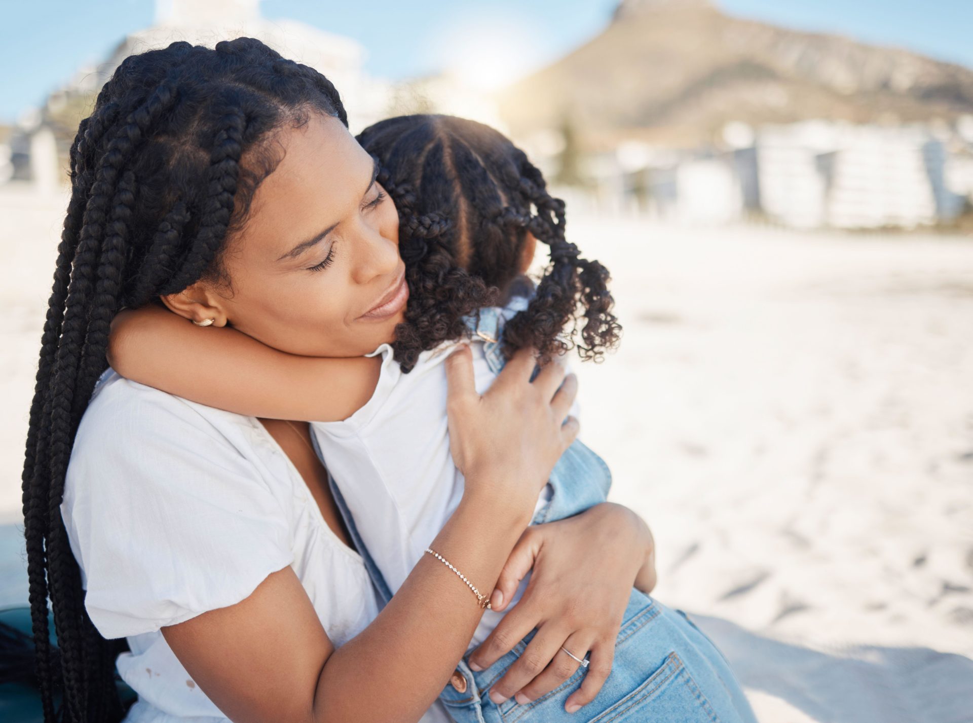 A mother hugs her child on the beach.