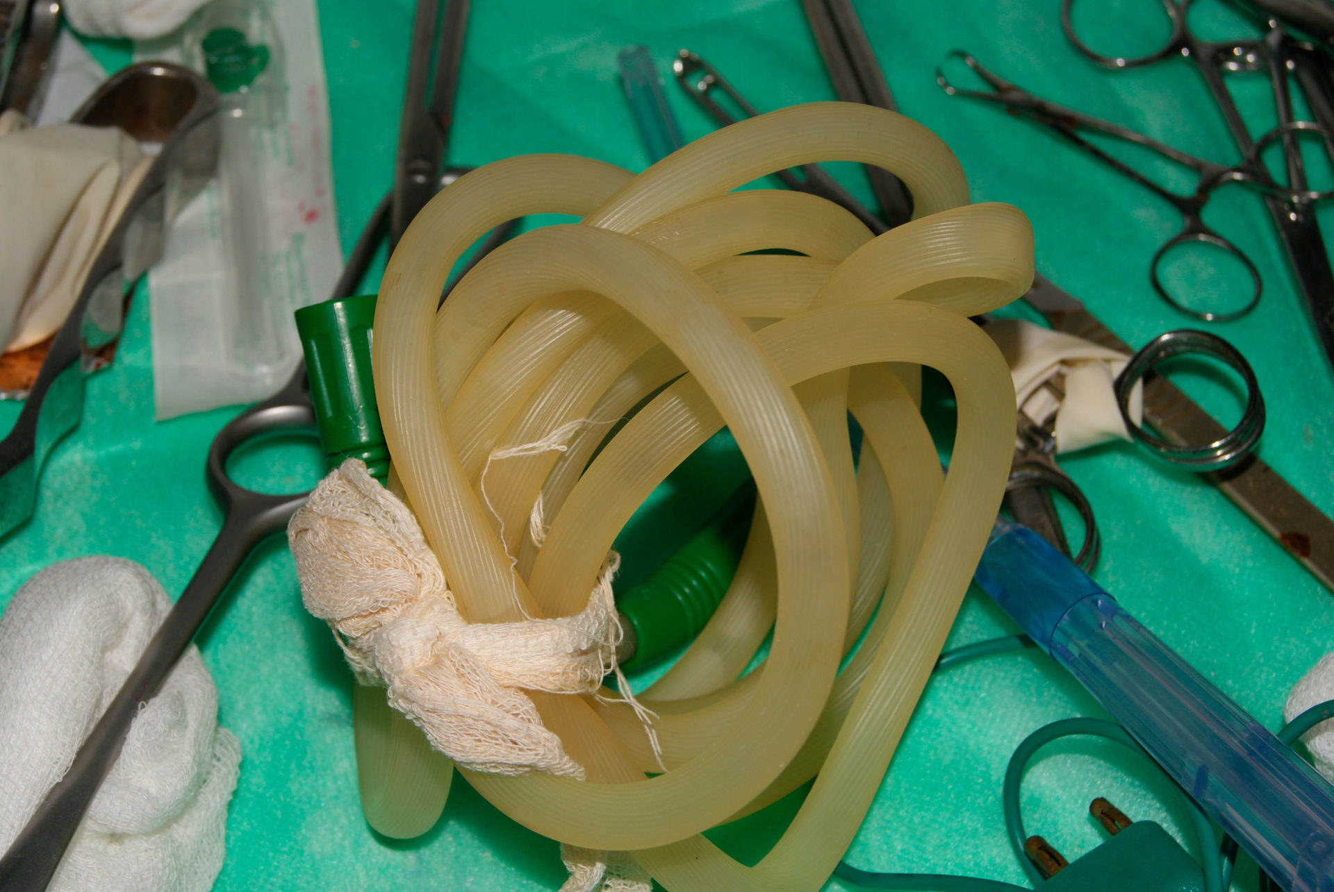 Medical tubes and other equipment lie on top of a green sheet.