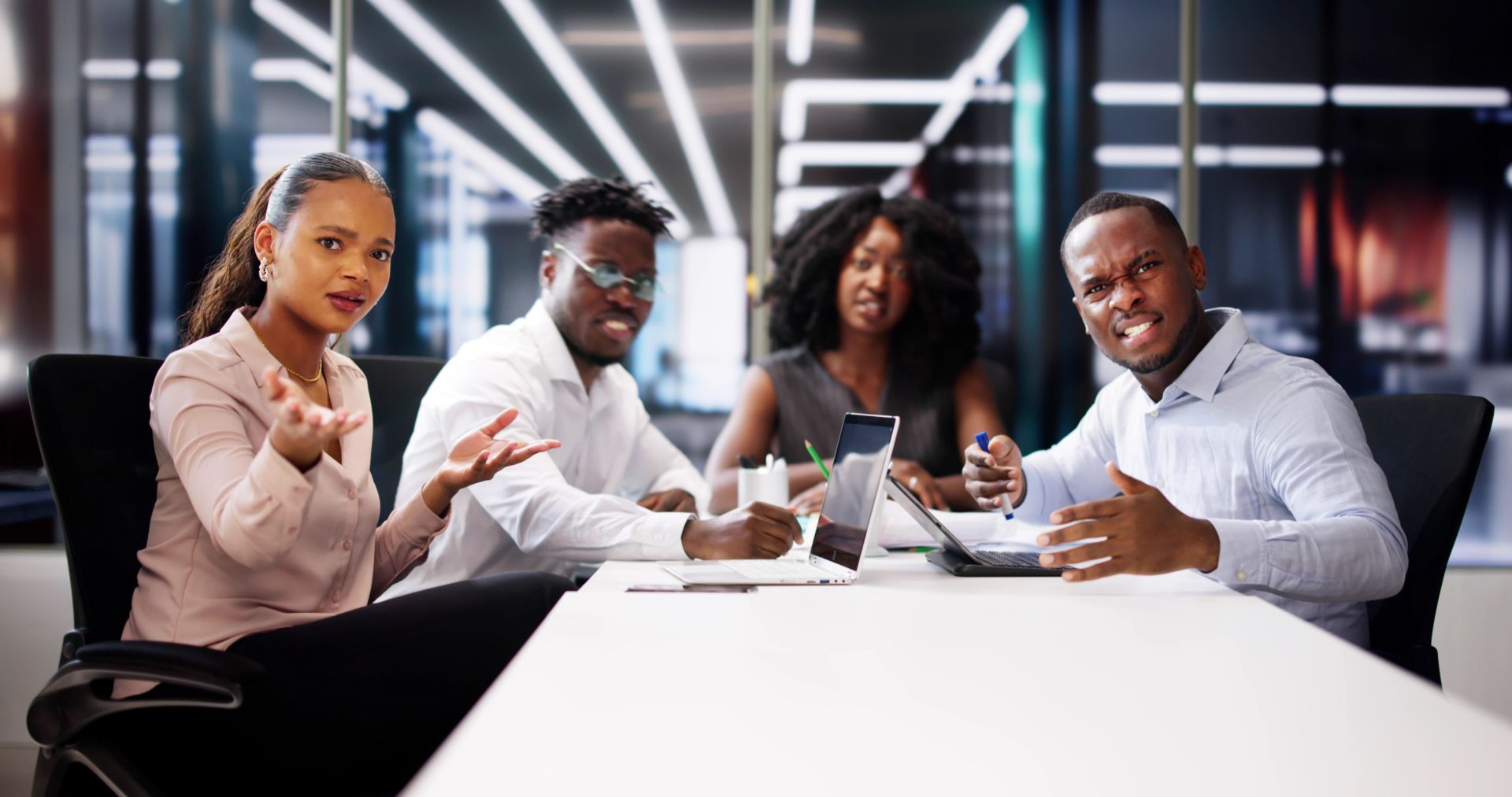 Angry group of people sit around a laptop in an office.