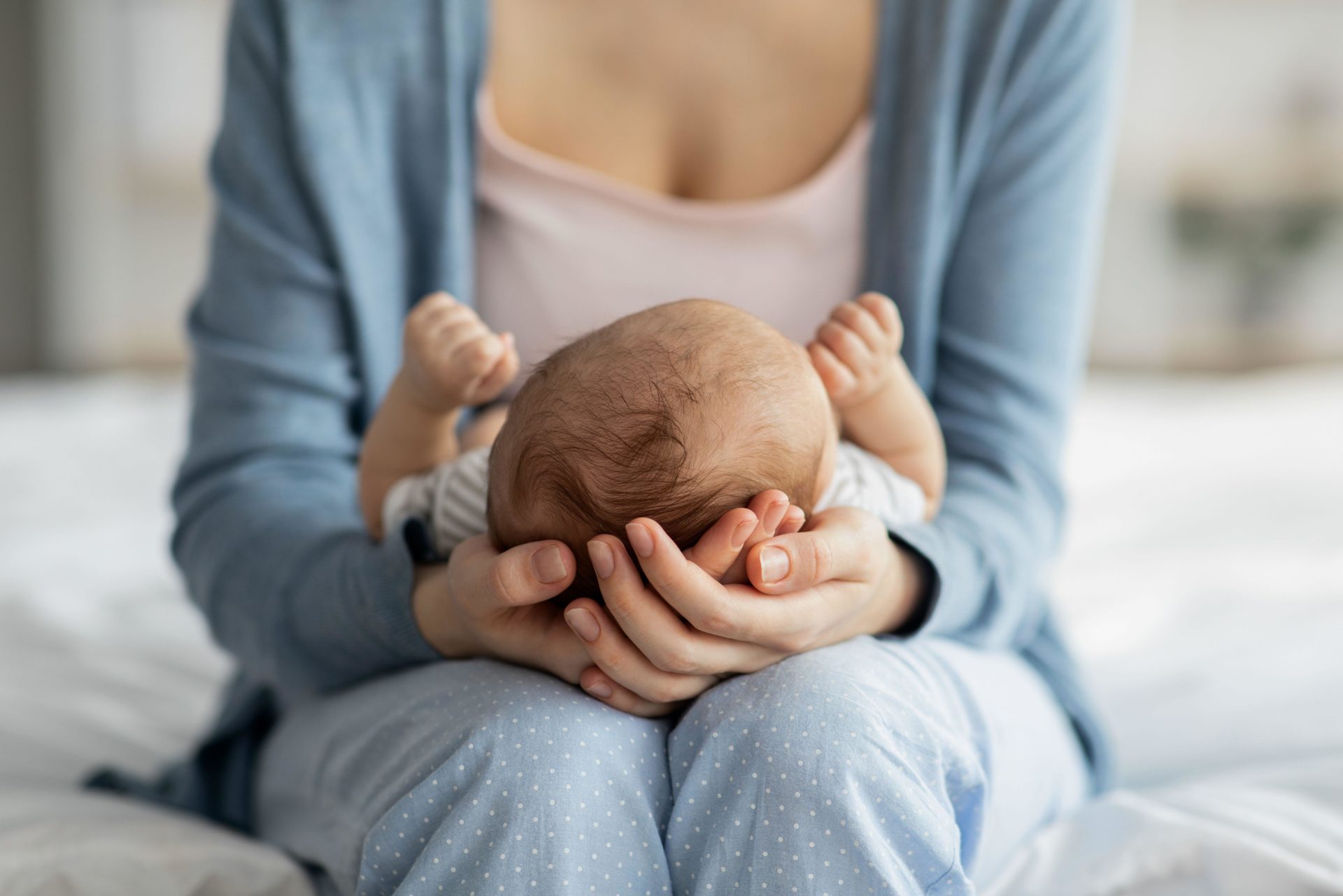 Mother Care. Unrecognizable mom holding newborn baby on her lap, Alamy.