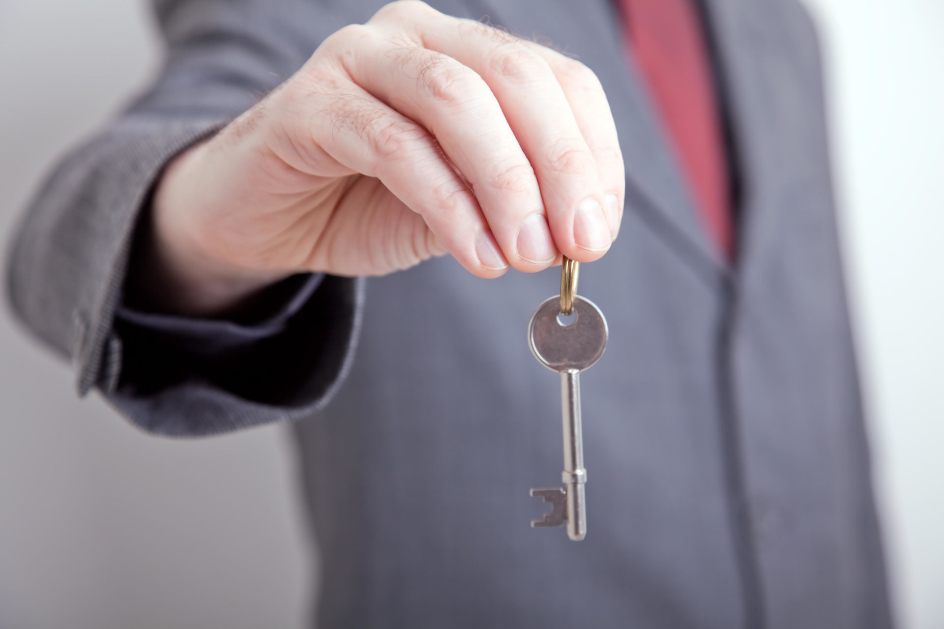 Person in a suit holding out a key.