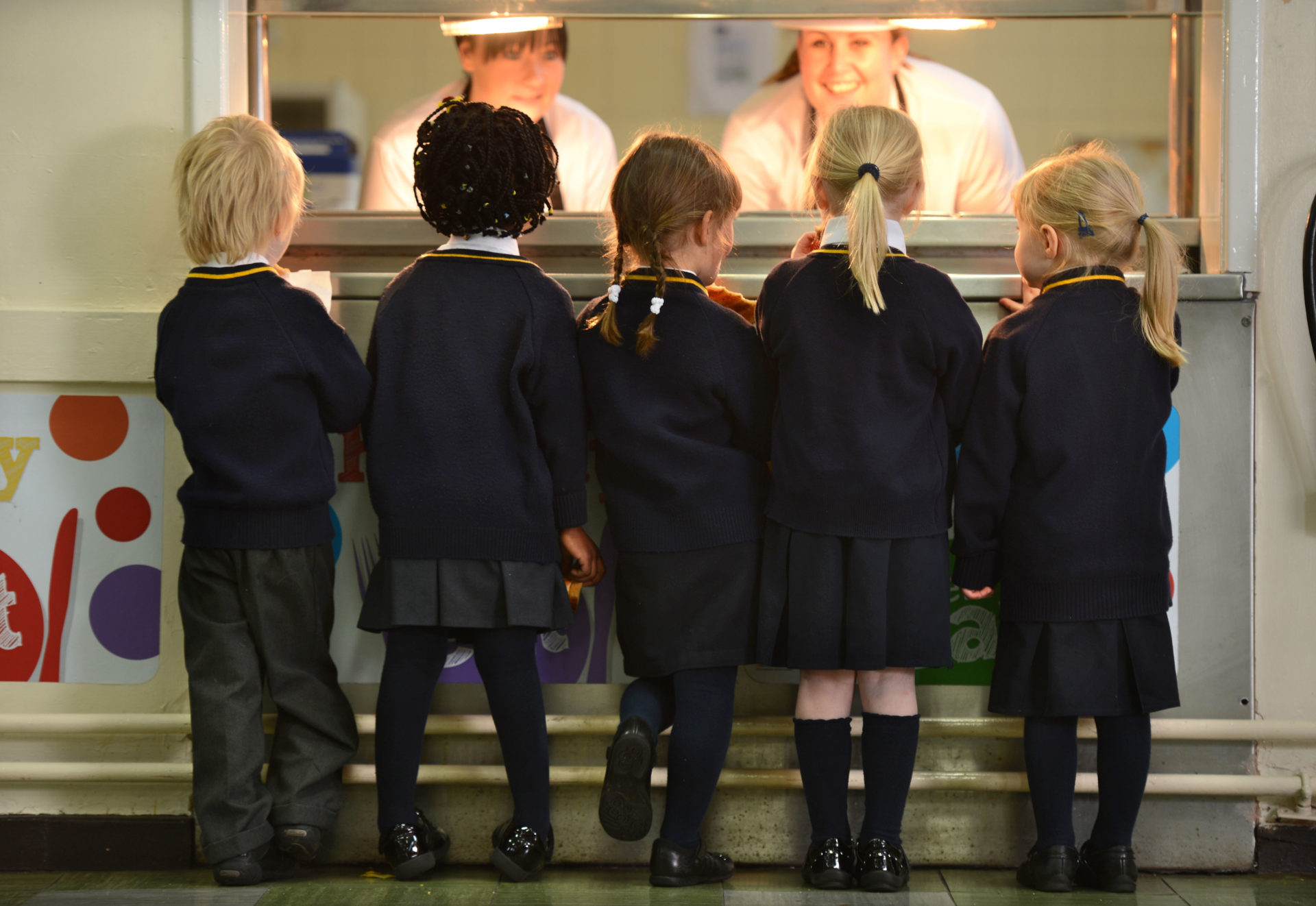 Children queue up for a meal in a school canteen