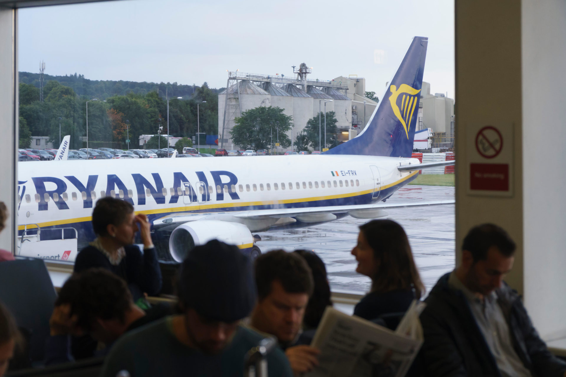 Passengers wait in the terminal at Dublin Aiport with a Ryanair flight outside. Image: Alamy