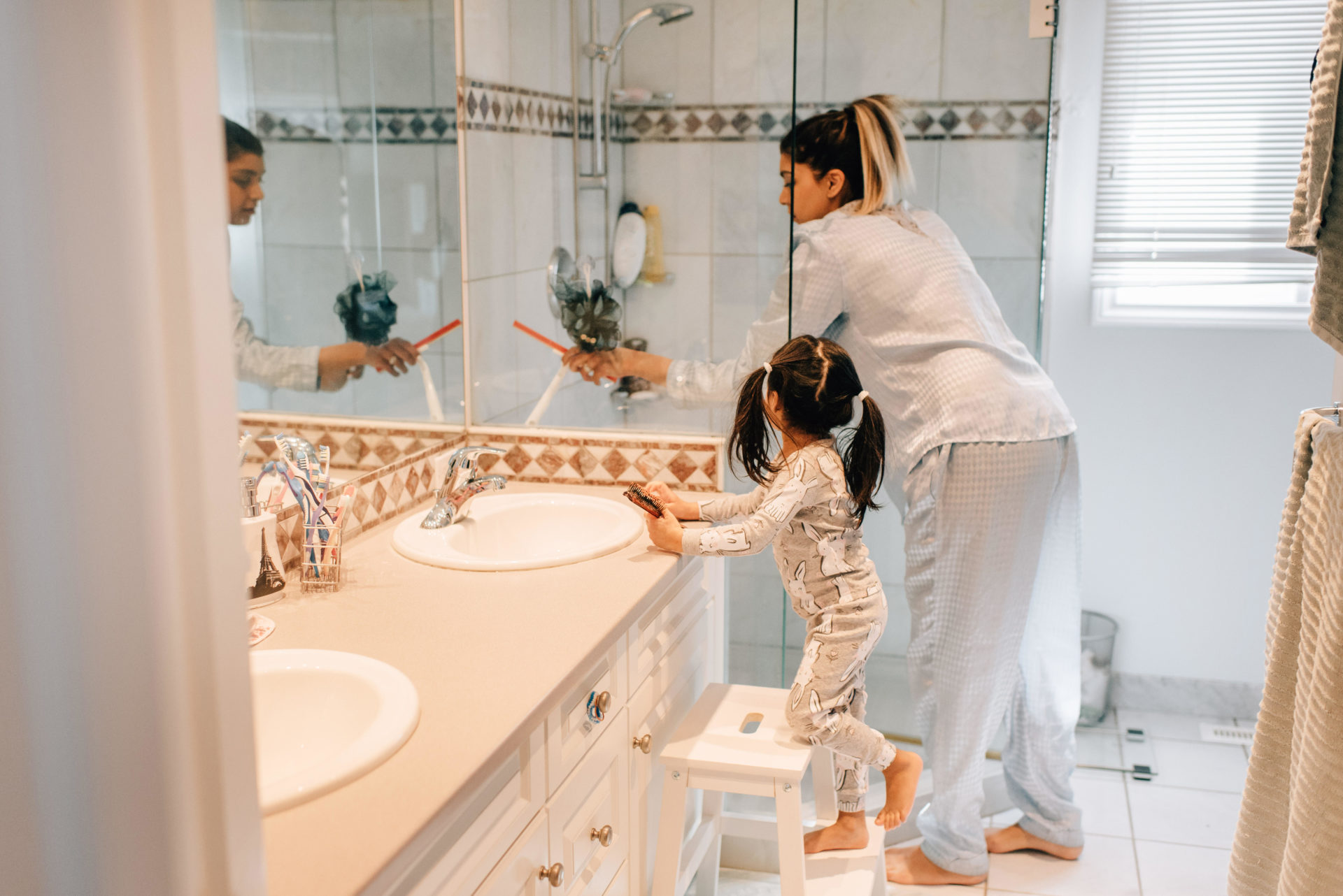 Girl and mother getting ready in bathroom.